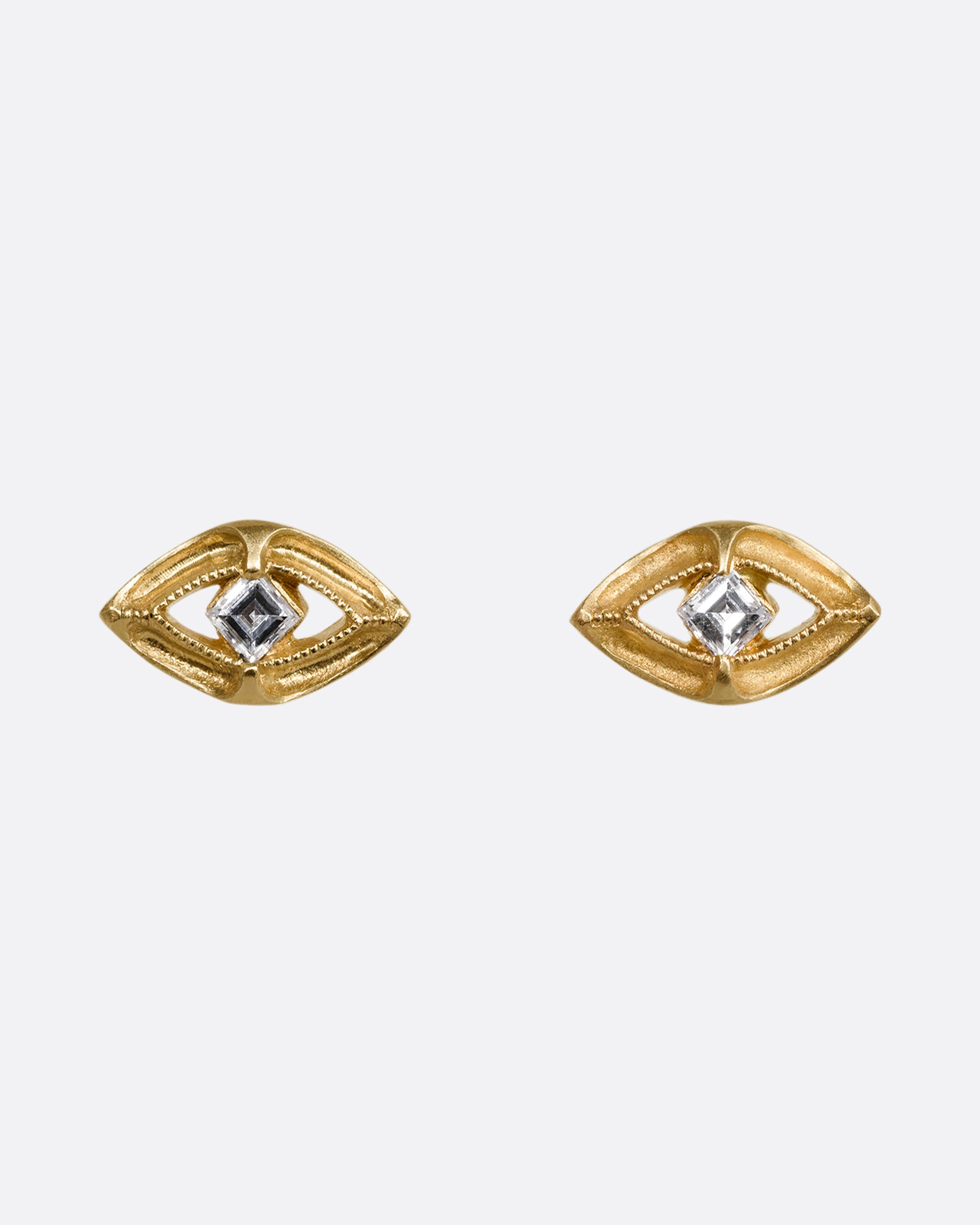A pair of yellow gold earrings shaped like an eye with a diamond at the center. Shown from the front.