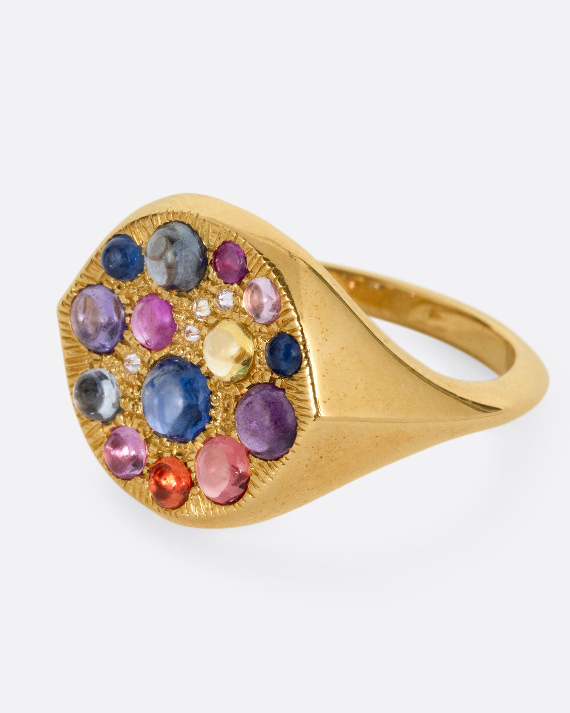 A yellow gold eye shaped ring with sapphire cabochons and diamonds, shown from the side.