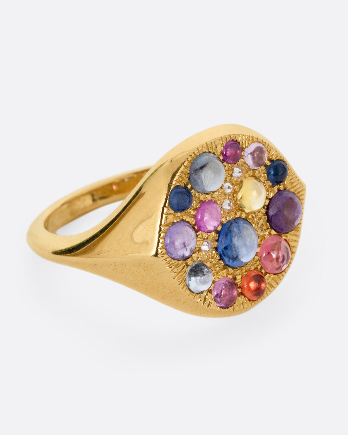 A yellow gold eye shaped ring with sapphire cabochons and diamonds, shown from the side.