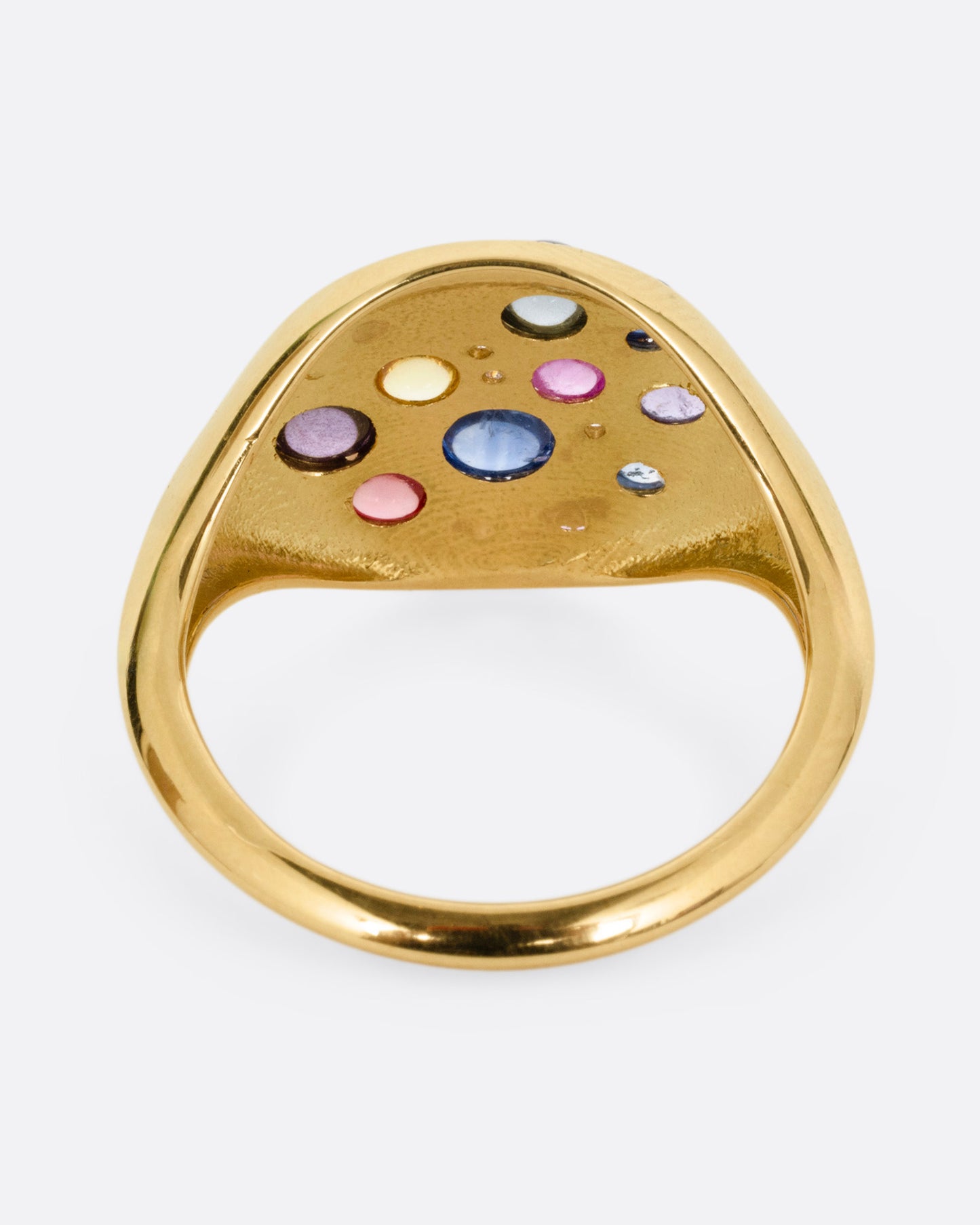 A yellow gold eye shaped ring with sapphire cabochons and diamonds, shown from the back.