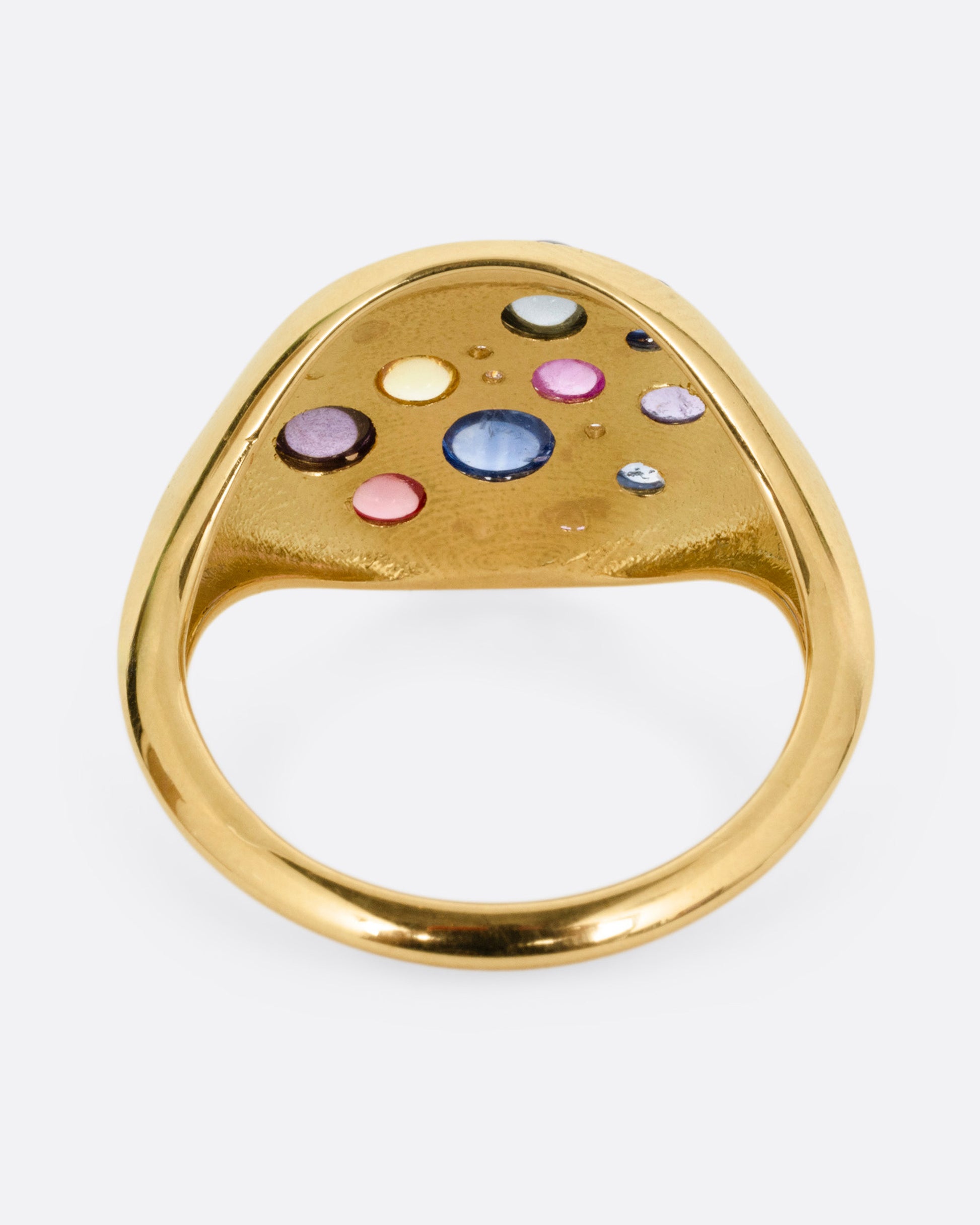 A yellow gold eye shaped ring with sapphire cabochons and diamonds, shown from the back.