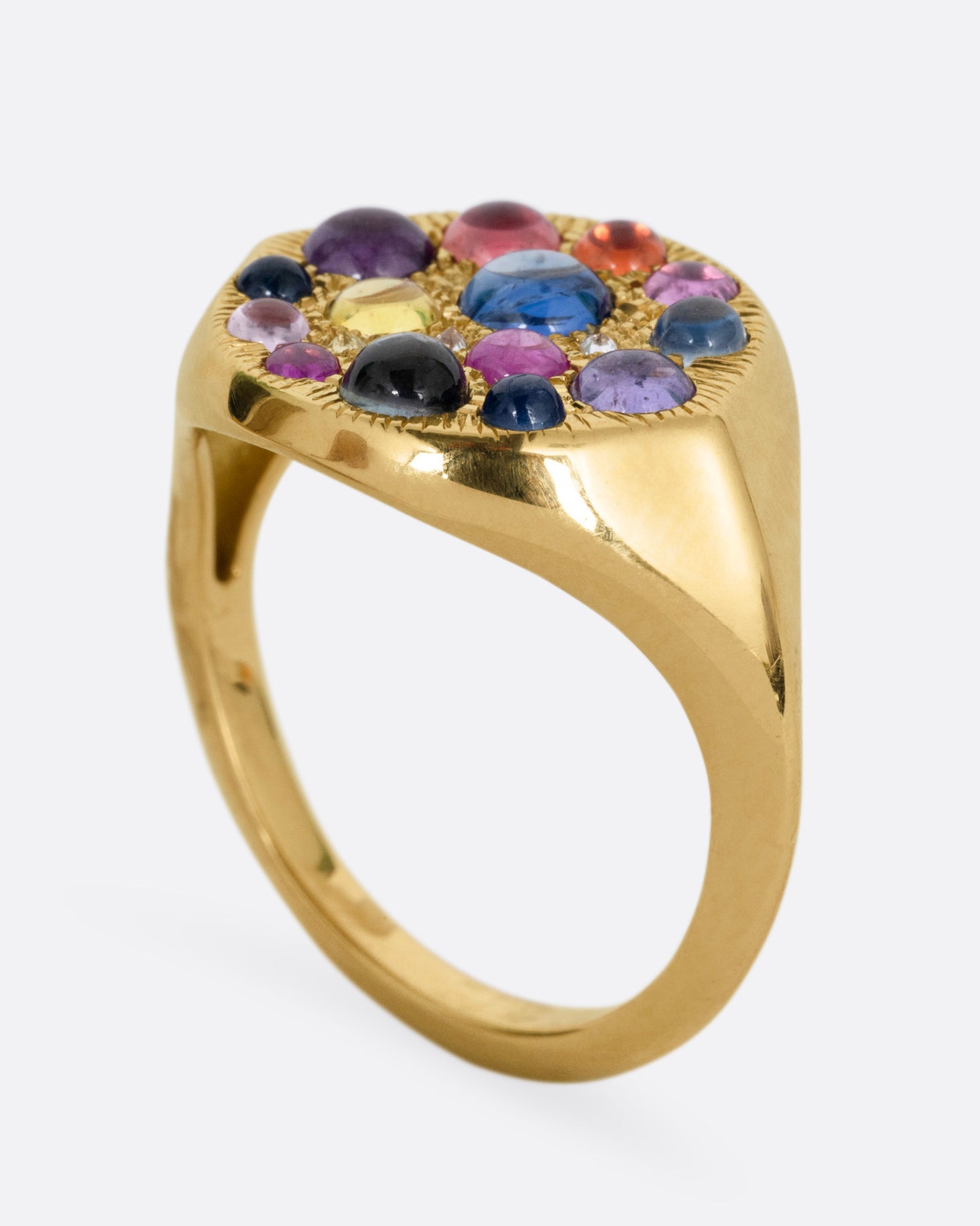 A yellow gold eye shaped ring with sapphire cabochons and diamonds, shown from the side standing up.