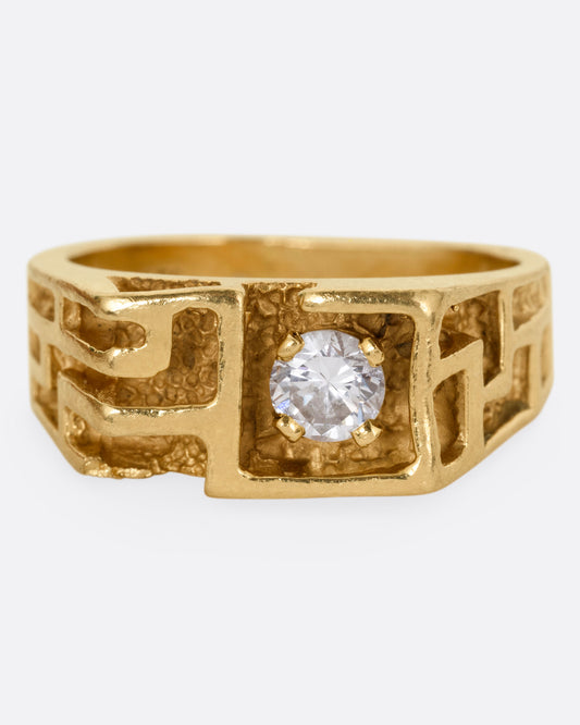 A yellow gold ring with a  labryinthian pattern and diamond, shown from the front.