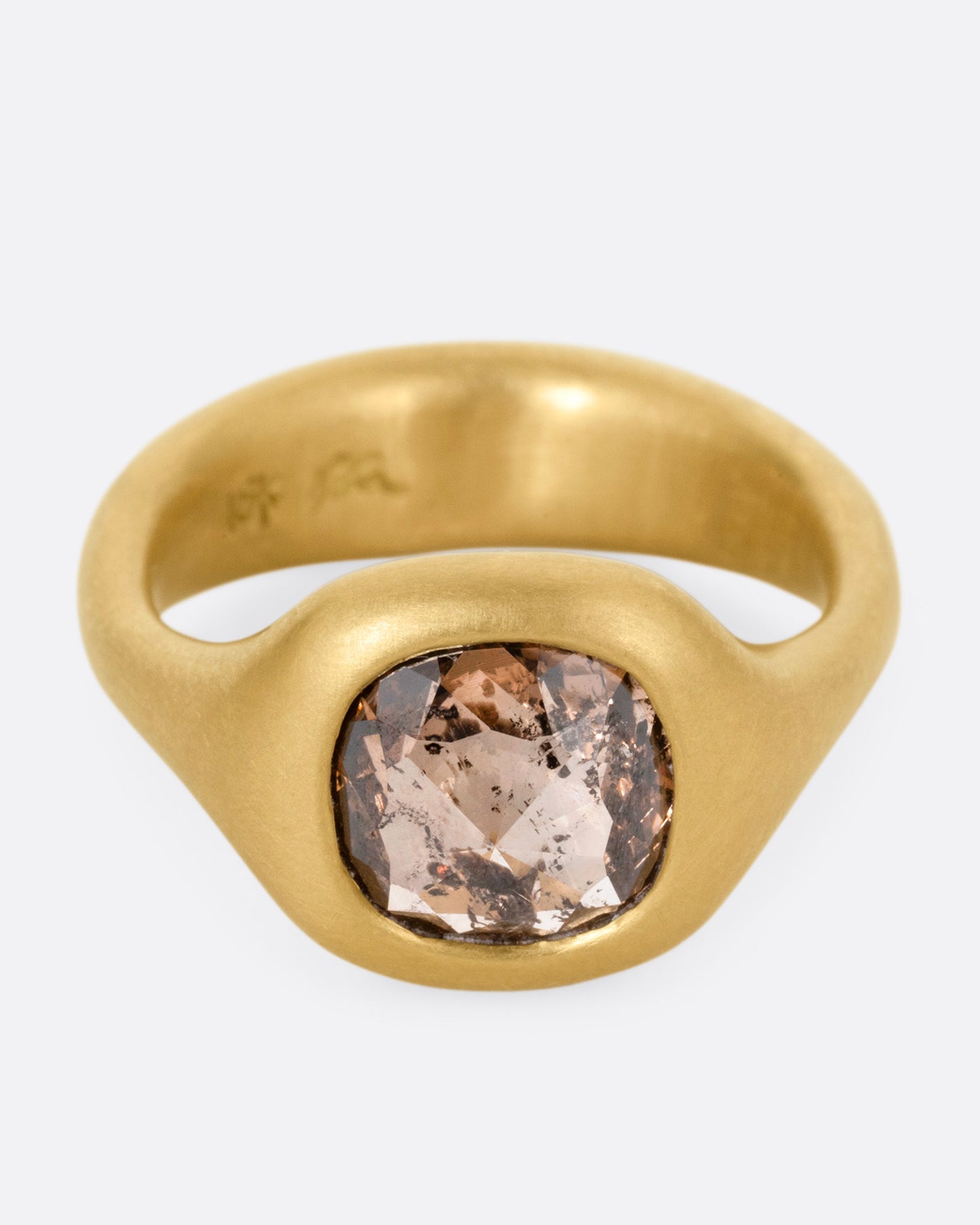 A yellow gold ring with a cognac diamond, shown from the front.