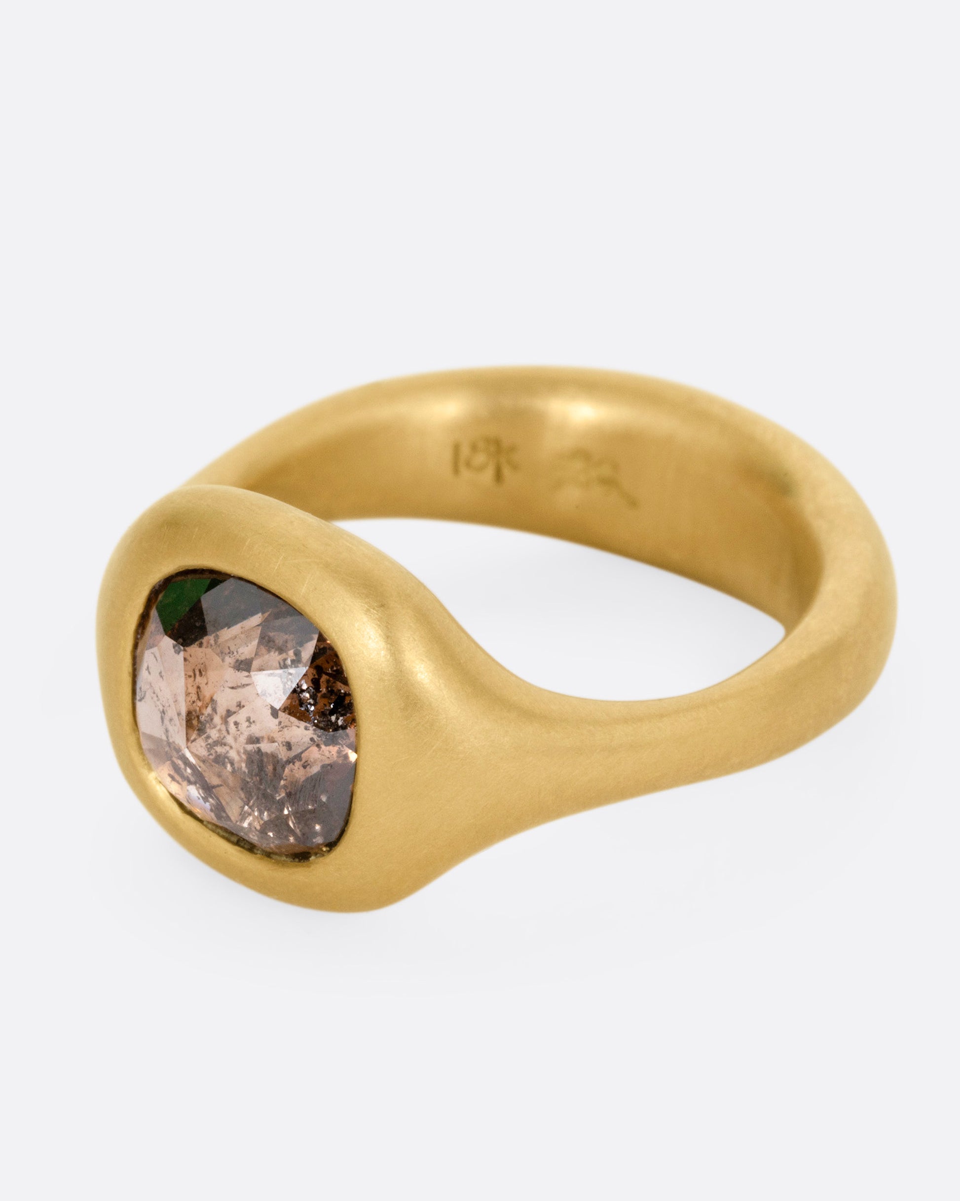 A yellow gold ring with a cognac diamond, shown from the side.