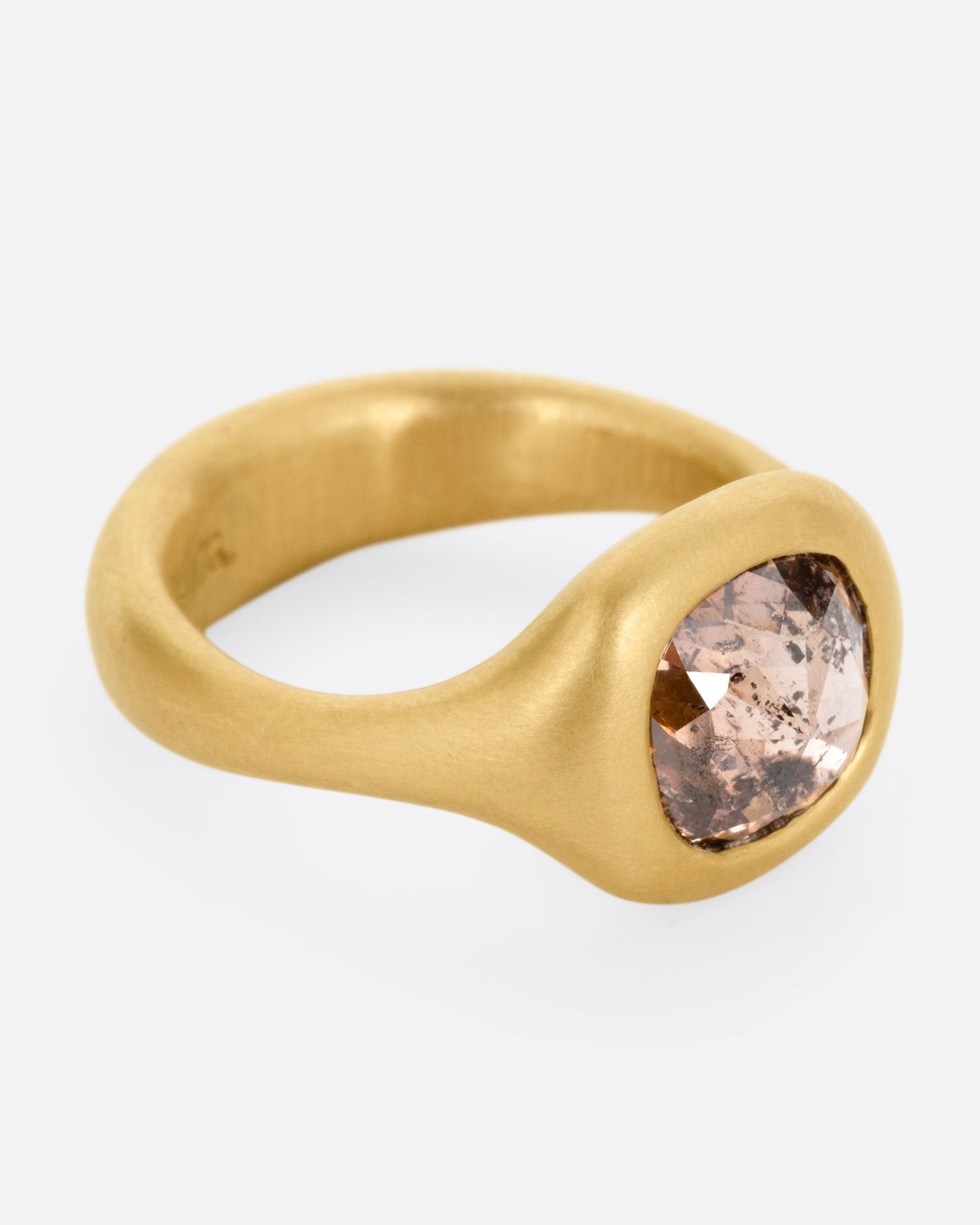 A yellow gold ring with a cognac diamond, shown from the front.
