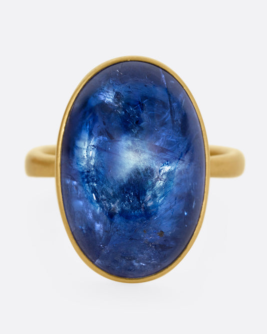 A yellow gold ring with a large blue oval tanzanite, shown from the front.