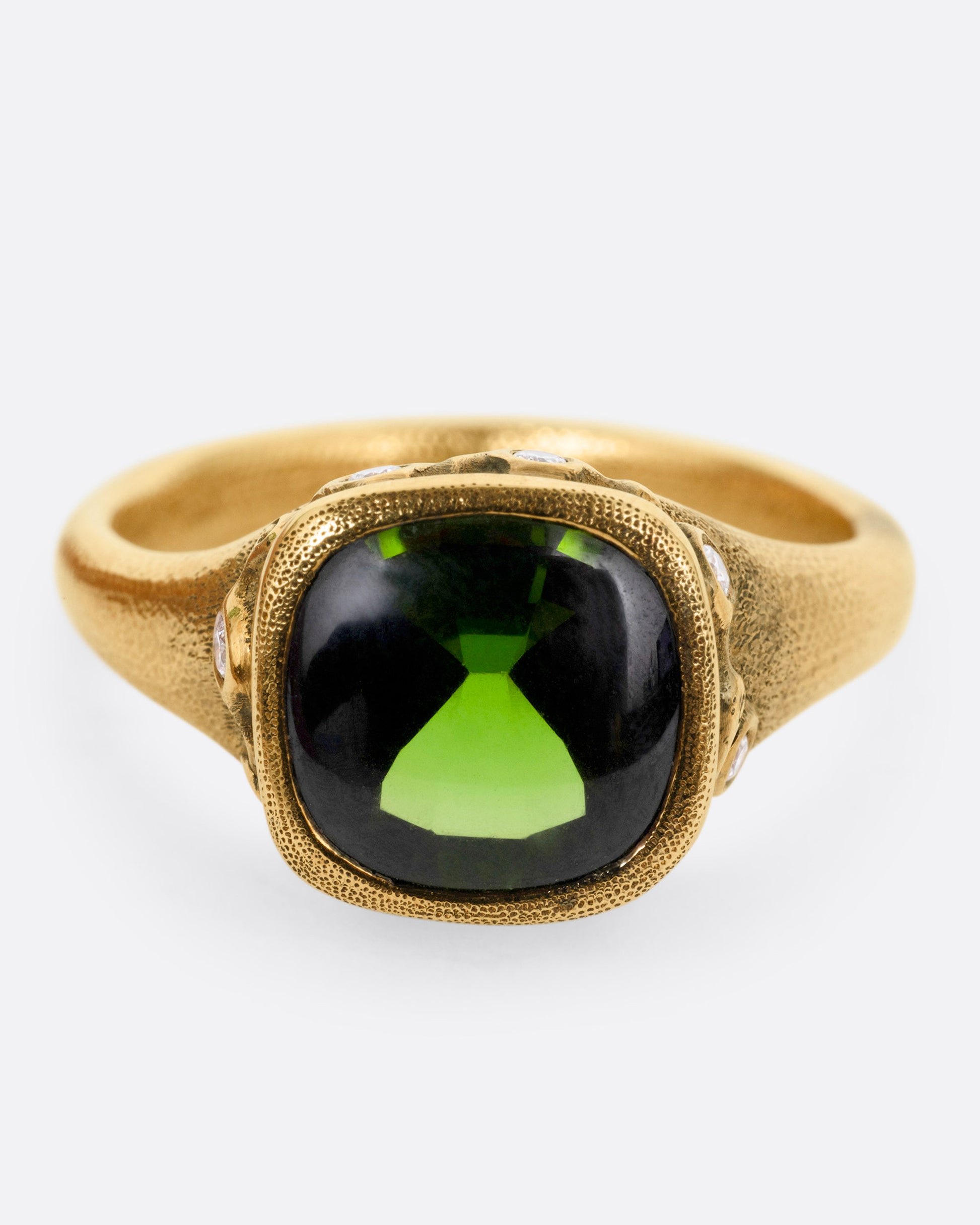 A yellow gold ring with a deep green tourmaline and white diamonds accents around its rounded edges. Shown from the front.