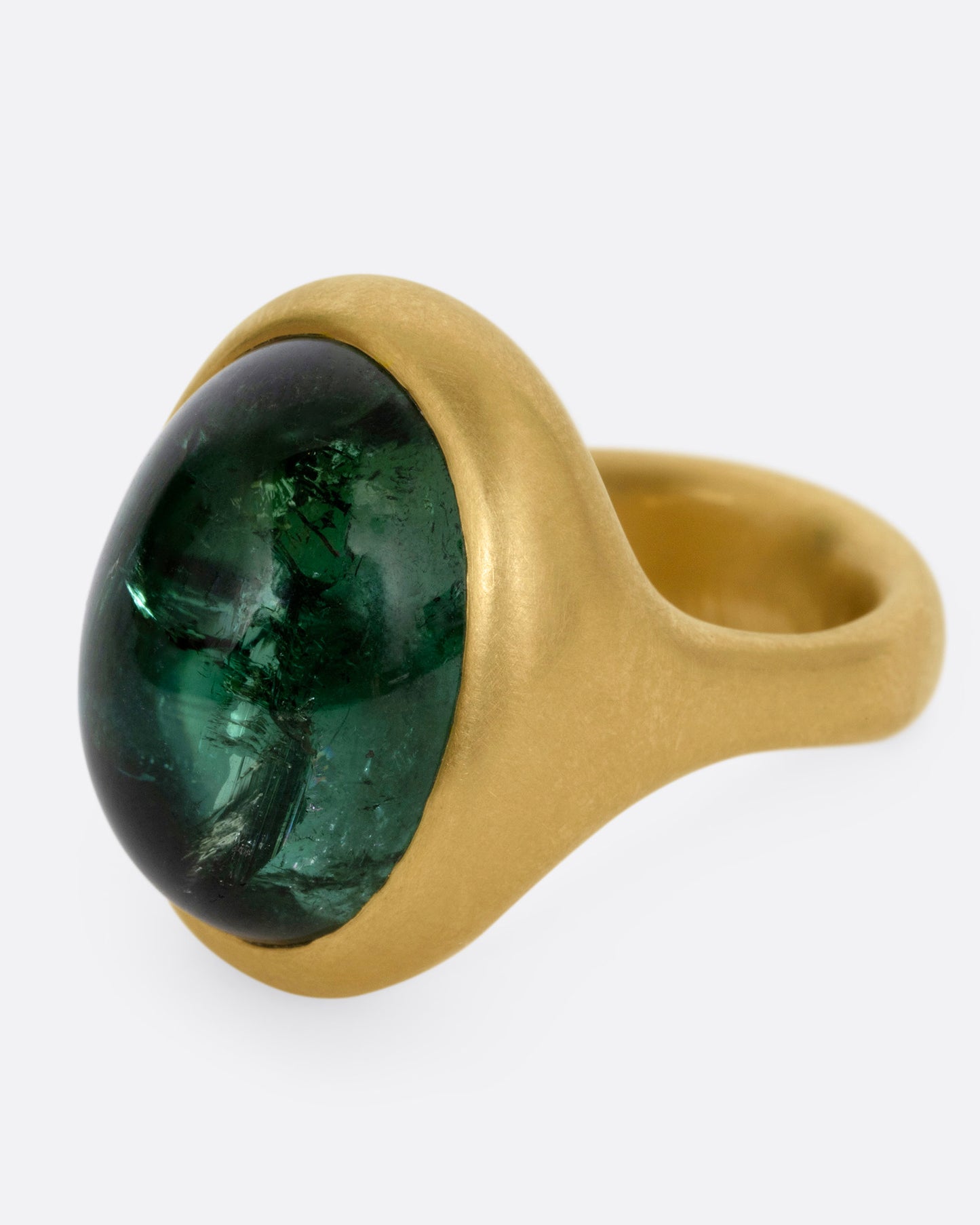 A yellow gold ring with a green tourmaline cabochon, shown from the side.