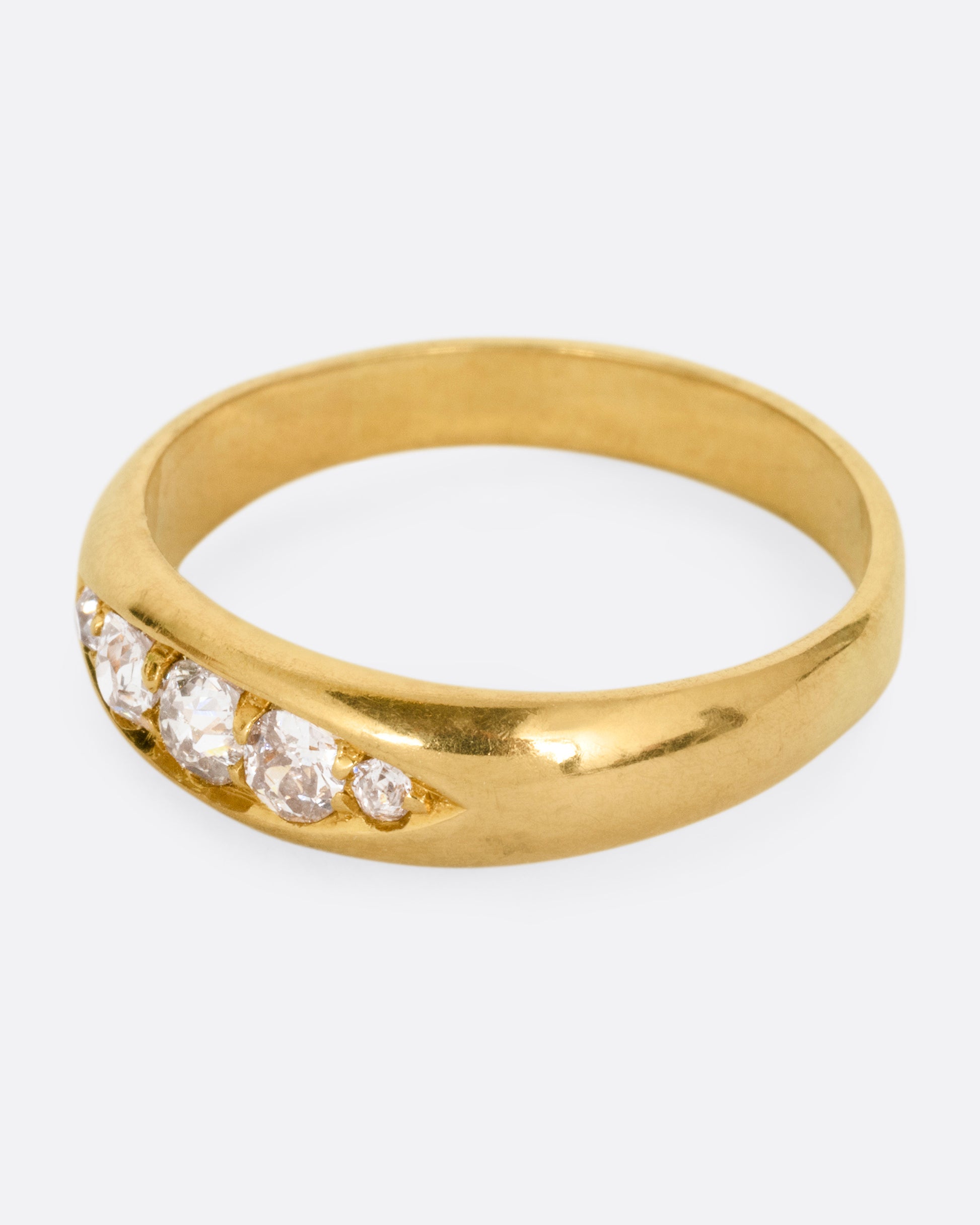 A yellow gold ring with five Old European cut diamonds, shown from the side.