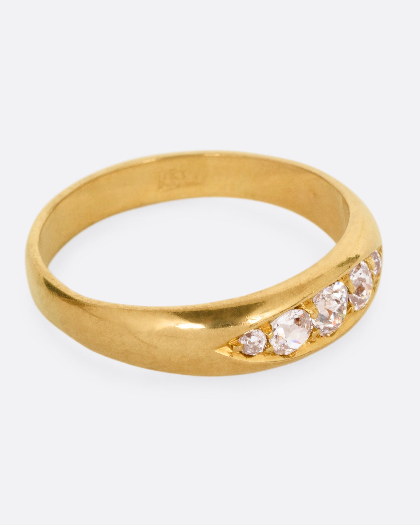 A yellow gold ring with five Old European cut diamonds, shown from the side.