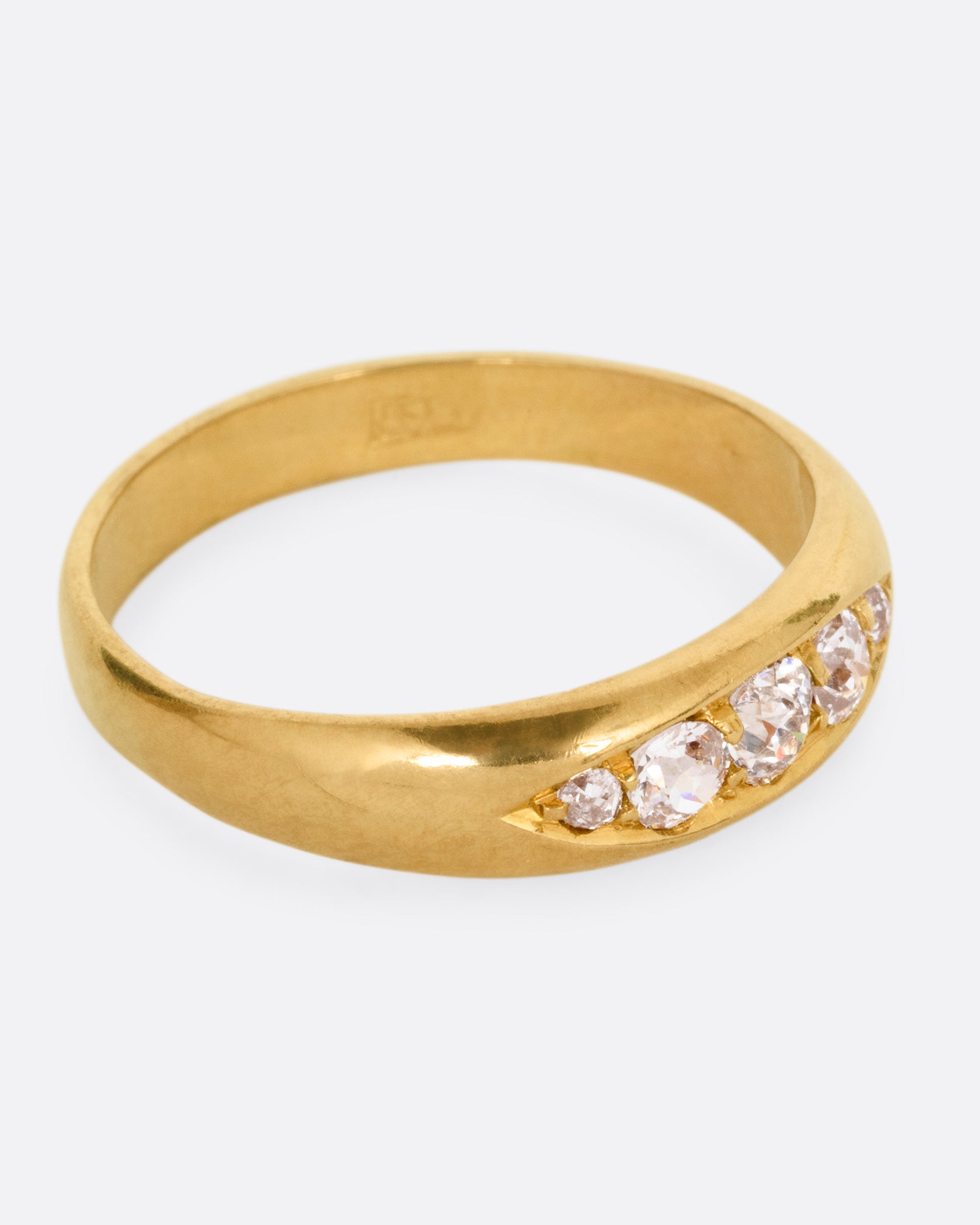 A yellow gold ring with five Old European cut diamonds, shown from the side.