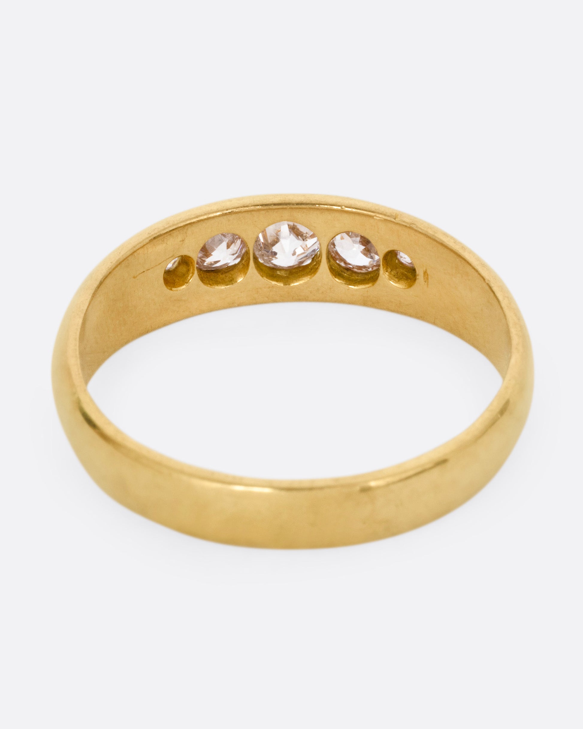 A yellow gold ring with five Old European cut diamonds, shown from the back.