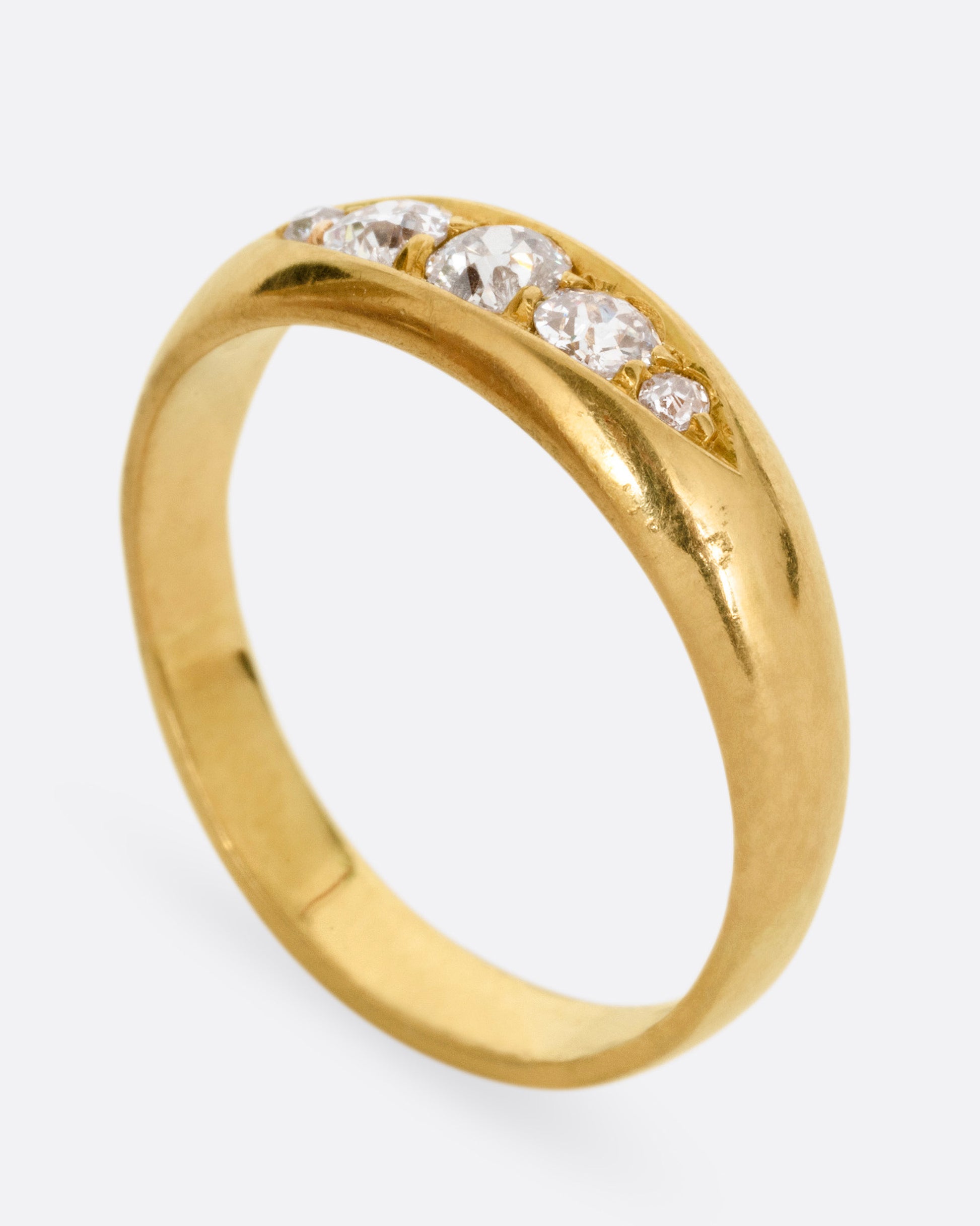 A yellow gold ring with five Old European cut diamonds, shown from the side standing up.