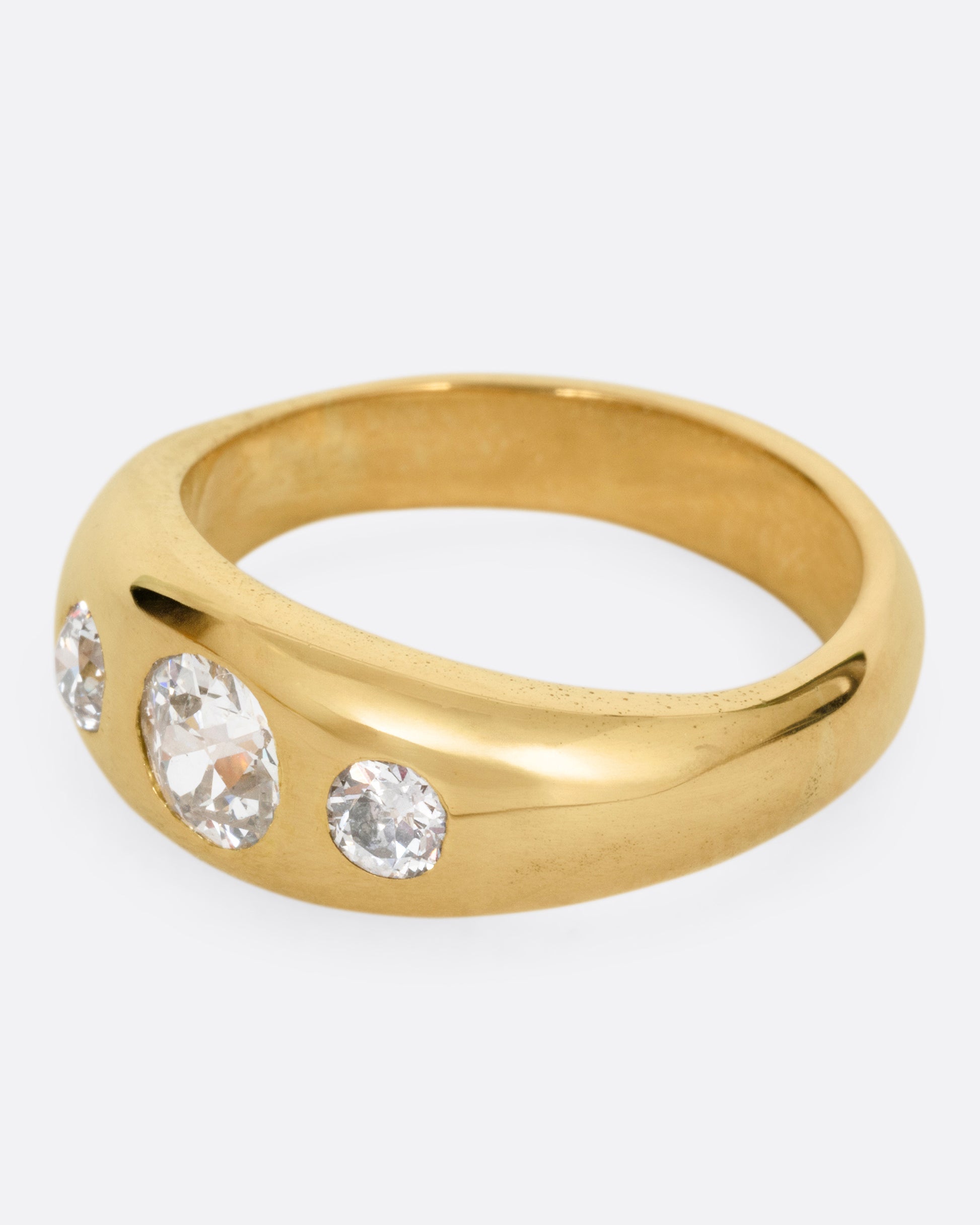 A yellow gold ring with three diamonds, shown from the side.