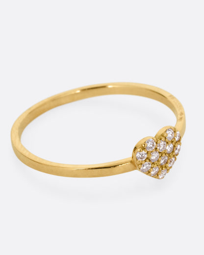 A yellow gold ring with a diamond studded heart. Shown from the side.