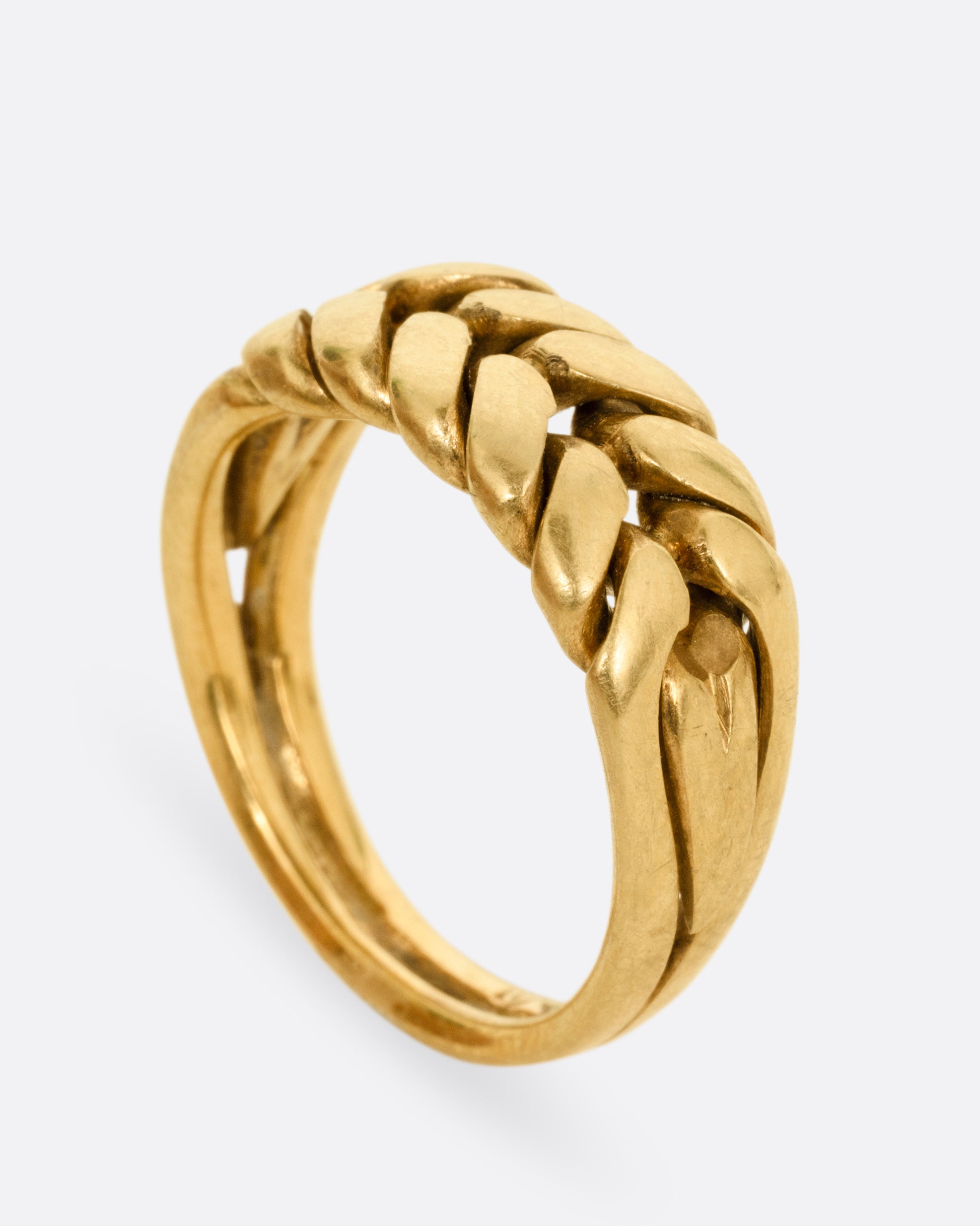 A yellow gold ring with a braided front. Shown from the side standing up.