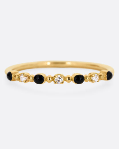 A yellow gold ring with three white diamonds and four black resin droplets, shown from the front.