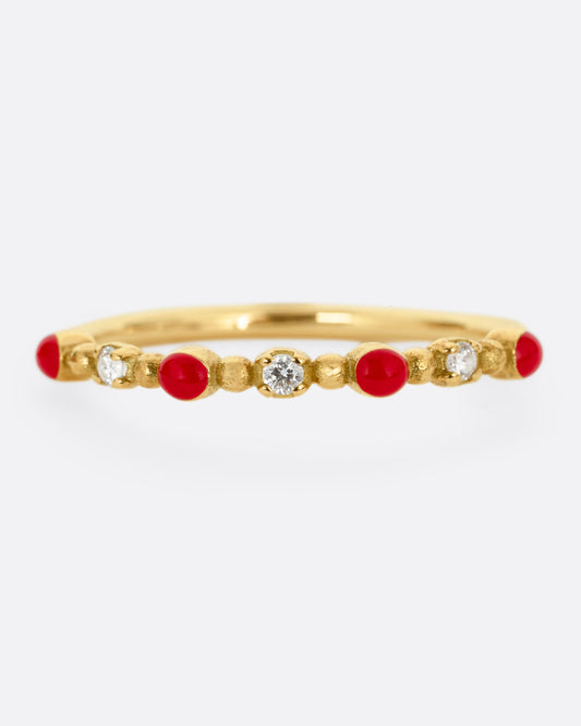 A yellow gold ring with three white diamonds and four red resin droplets, shown from the front.