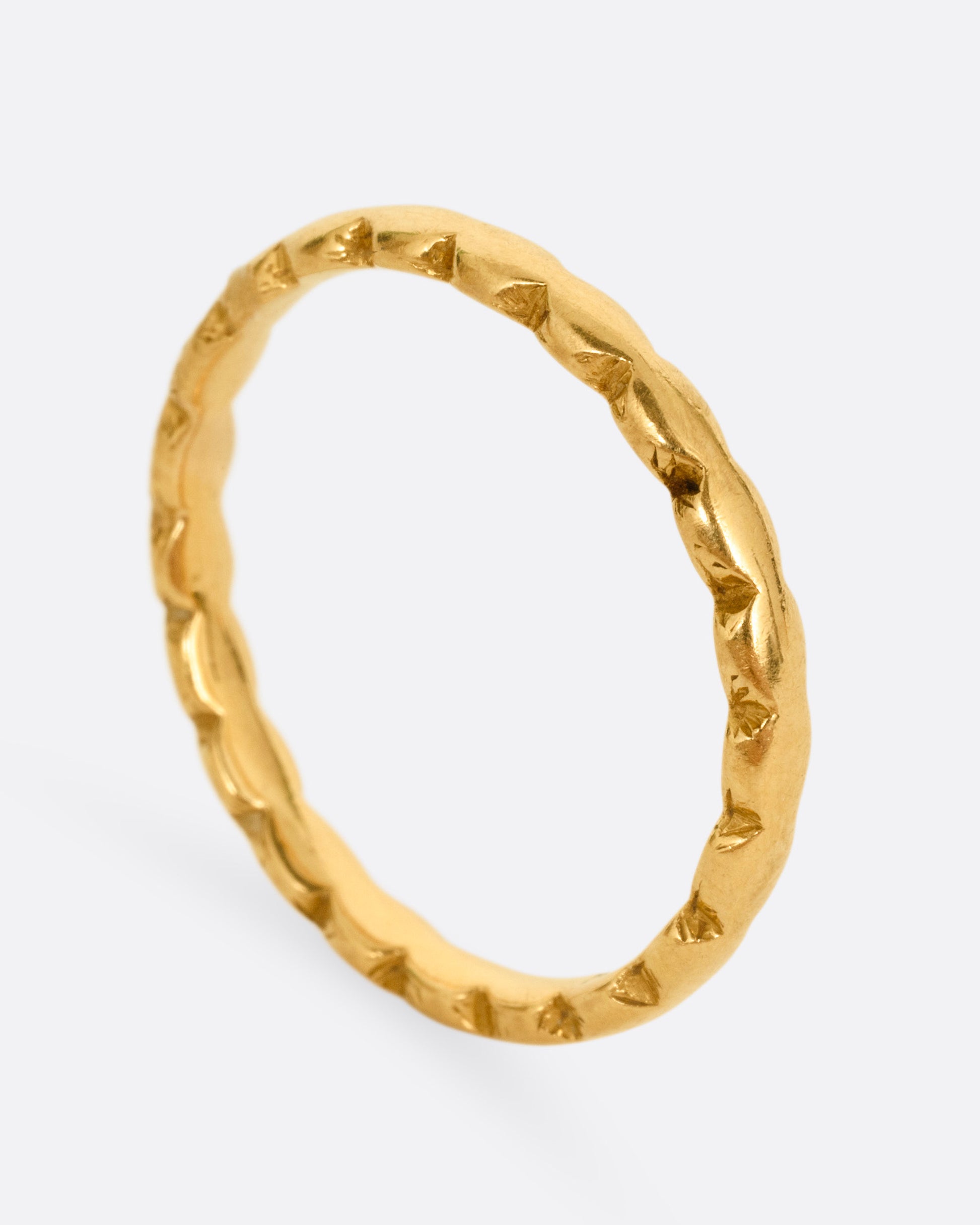 A yellow gold ring with scalloped edges. Shown from the side standing up.