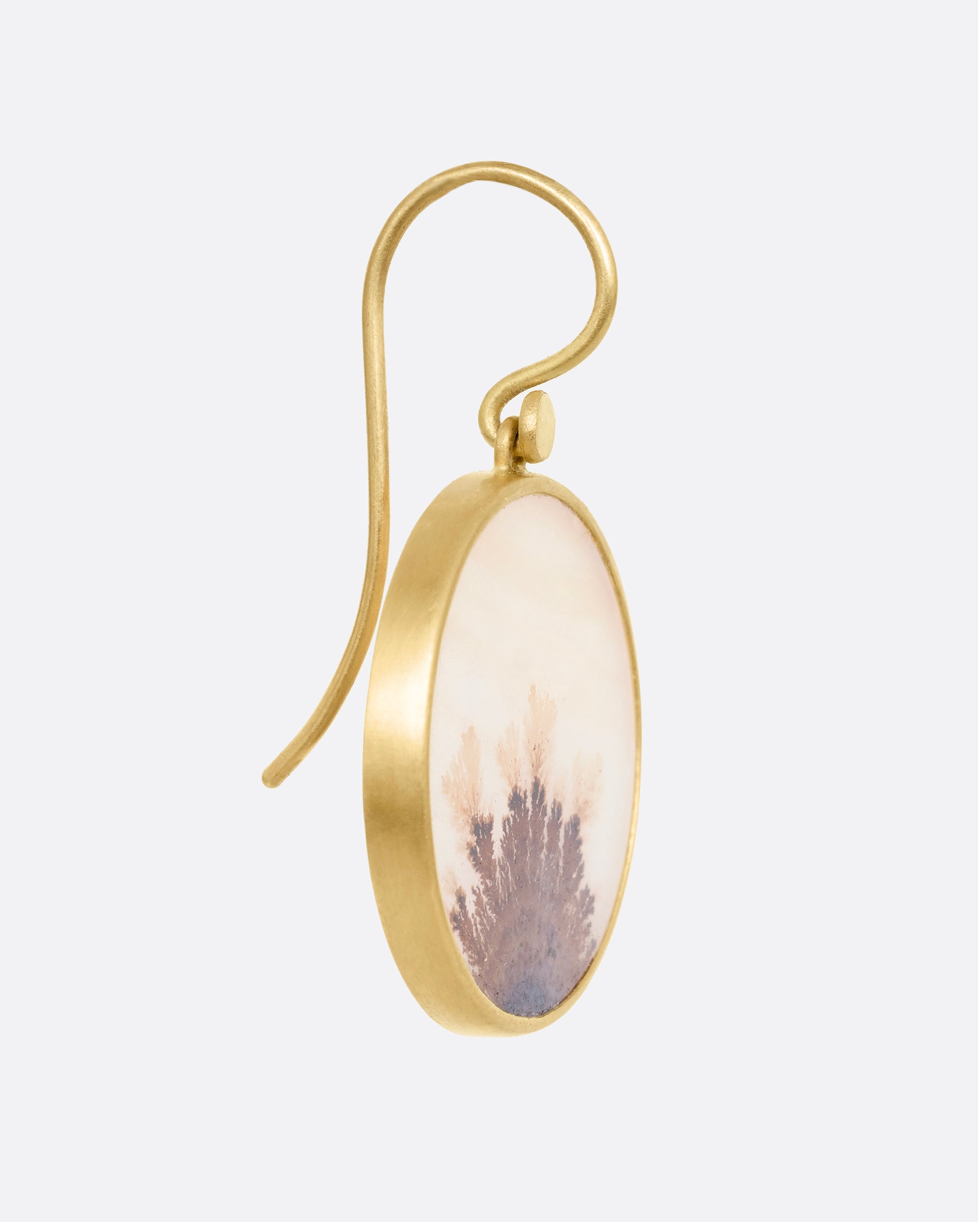 A yellow gold dendritic agate earring, shown from the side.