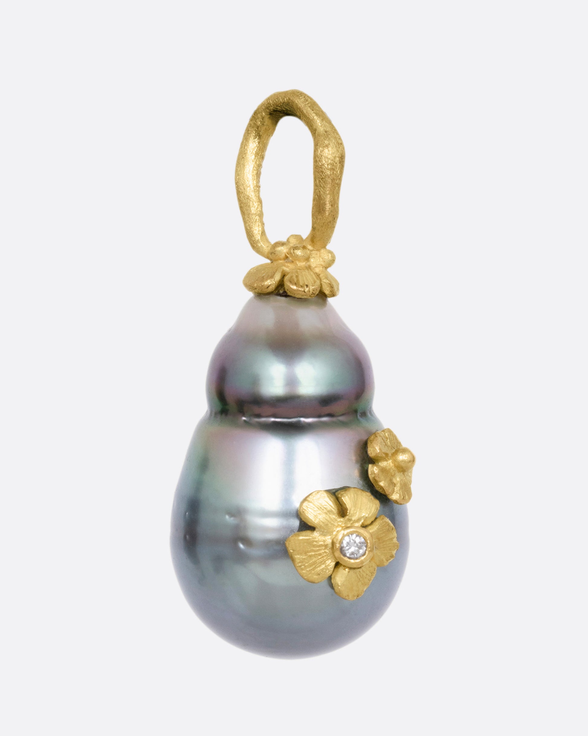 A yellow gold  Tahitian pearl pendant with diamond accented flower details, shown from the side.