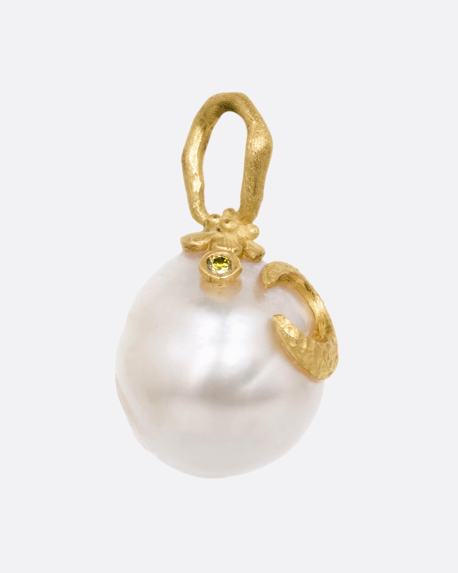 A yellow gold South Sea pearl pendant with a floral vine bail, a crescent moon, and a tiny diamond star. Shown from the side.