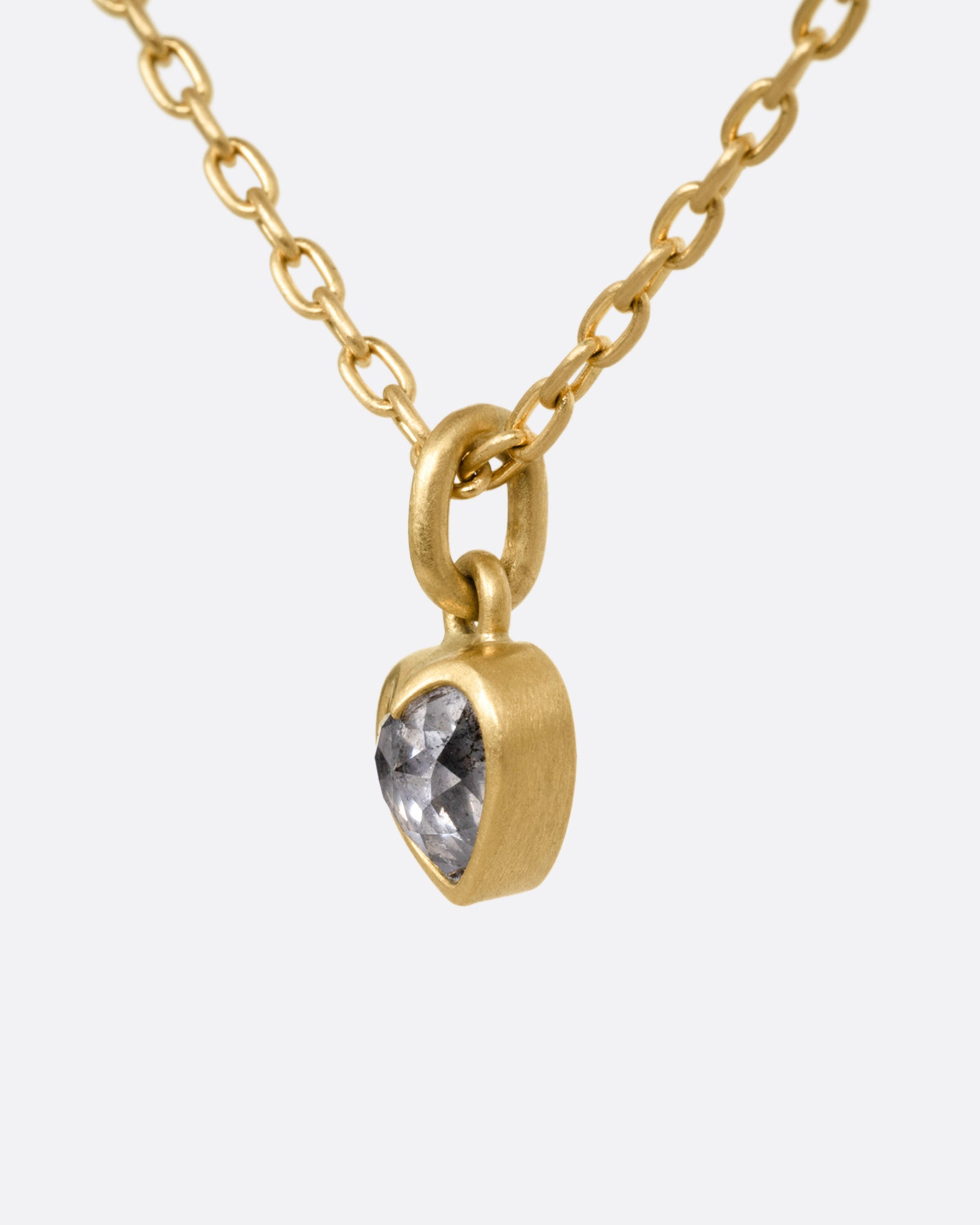 A yellow gold cable chain necklace with a dimensional diamond heart pendant, shown from the side.