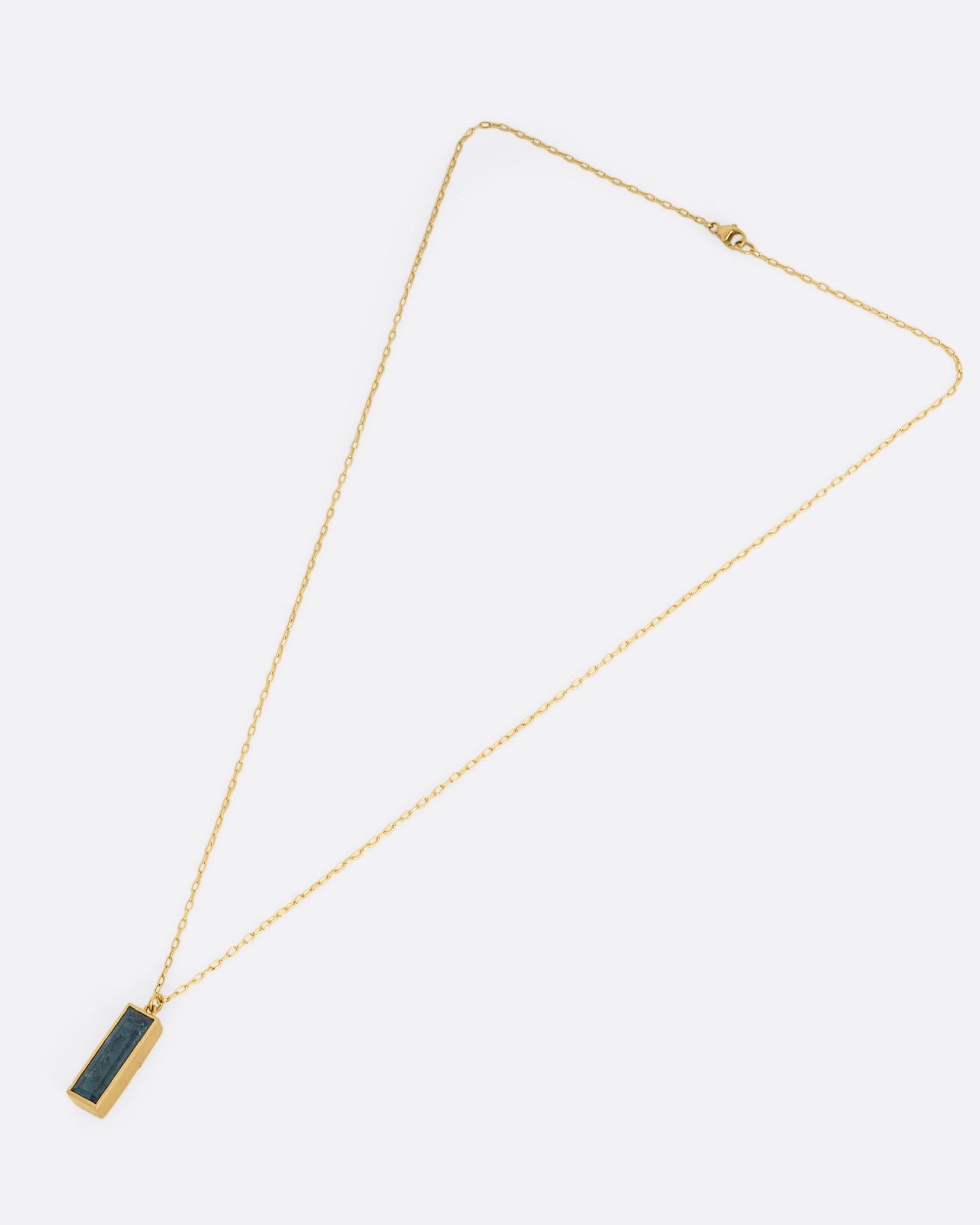 A yellow gold pendant necklace with a blue tourmaline slab, shown from the front.