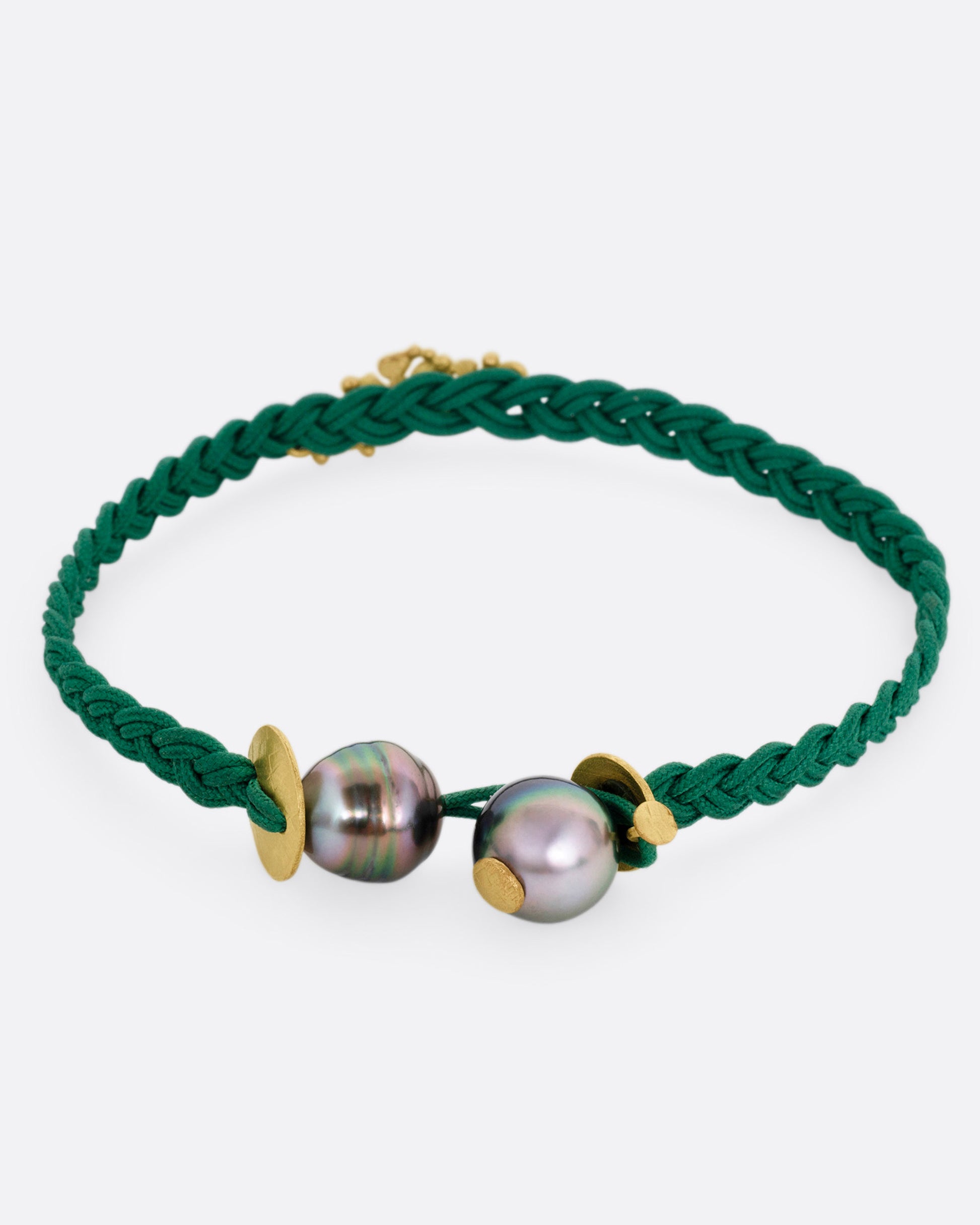 A braided green cord bracelet with a yellow gold cluster of diamond accented flowers and a Tahitian pearl toggle closure. Shown from the back.