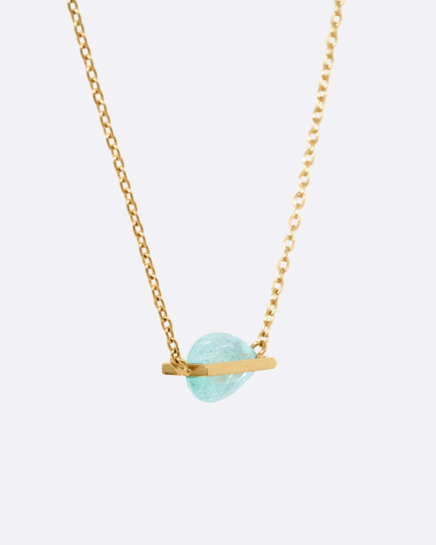 A yellow gold cable chain necklace with a blue-green Paraiba tourmaline pendant, shown from the side.