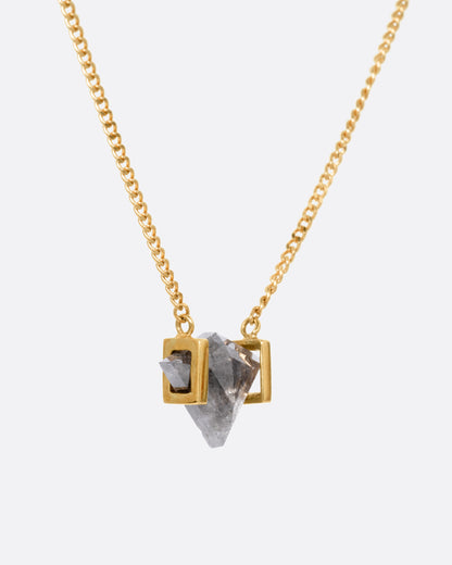 A yellow gold necklace with a salt and pepper diamond pendant, shown from the side.