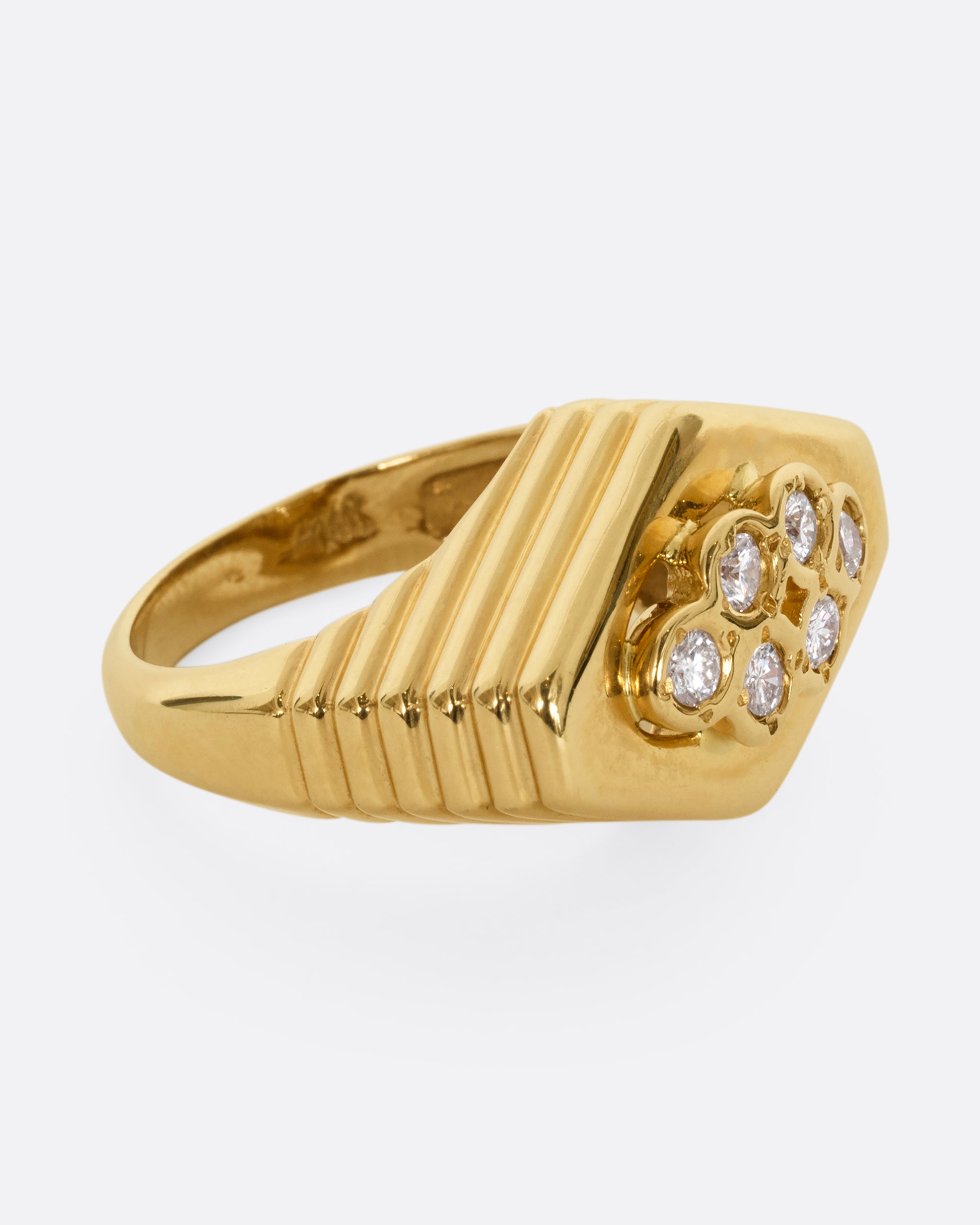 A yellow gold squared diamond shaped ring with a ribbed base and six round diamonds on the face. Shown from the side.