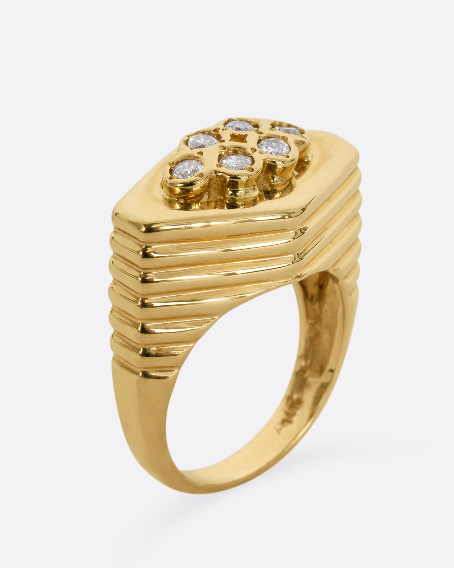 A yellow gold squared diamond shaped ring with a ribbed base and six round diamonds on the face. Shown from the side, standing up.