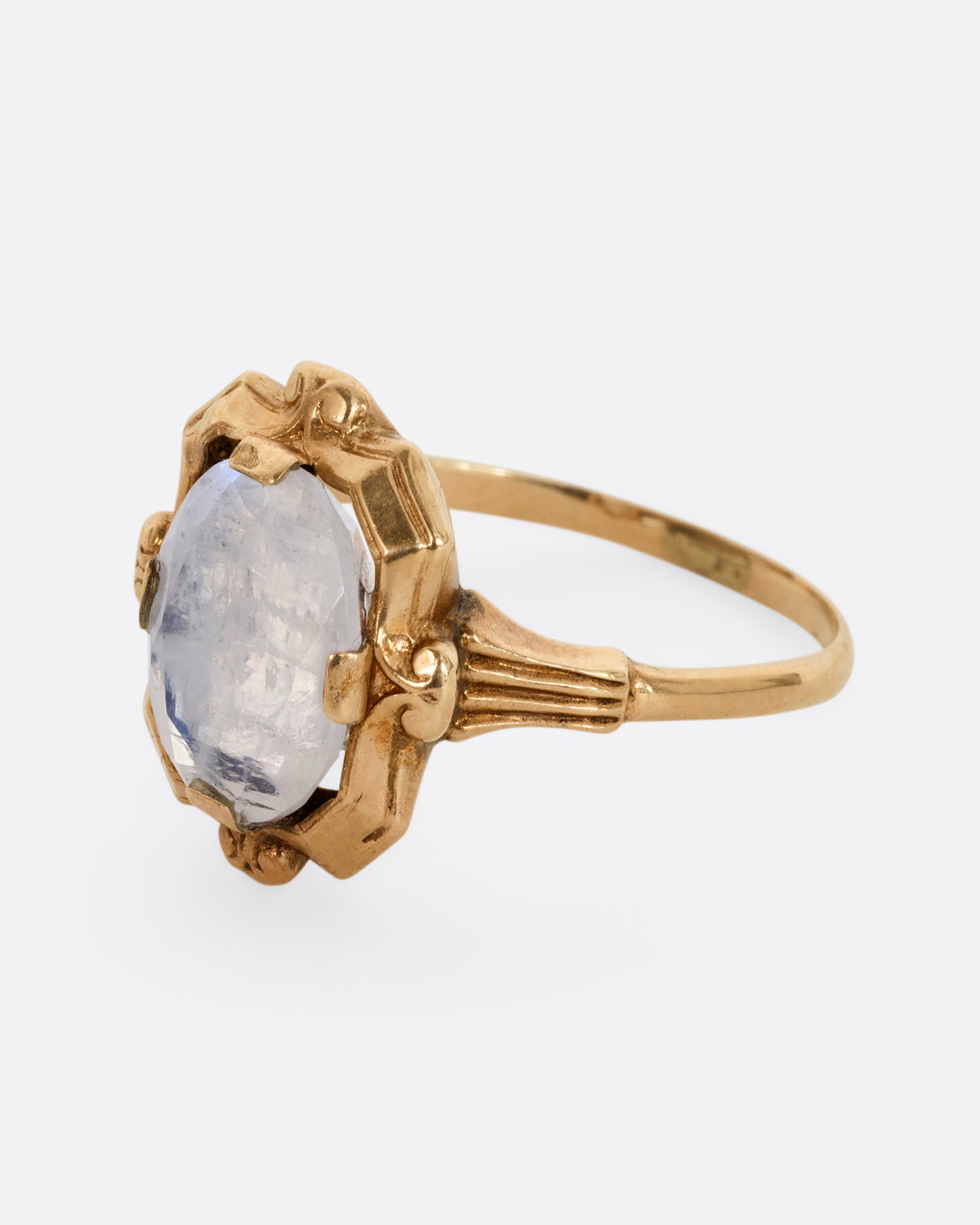 A yellow gold frame shaped ring with a moonstone at the center. Shown from the side.