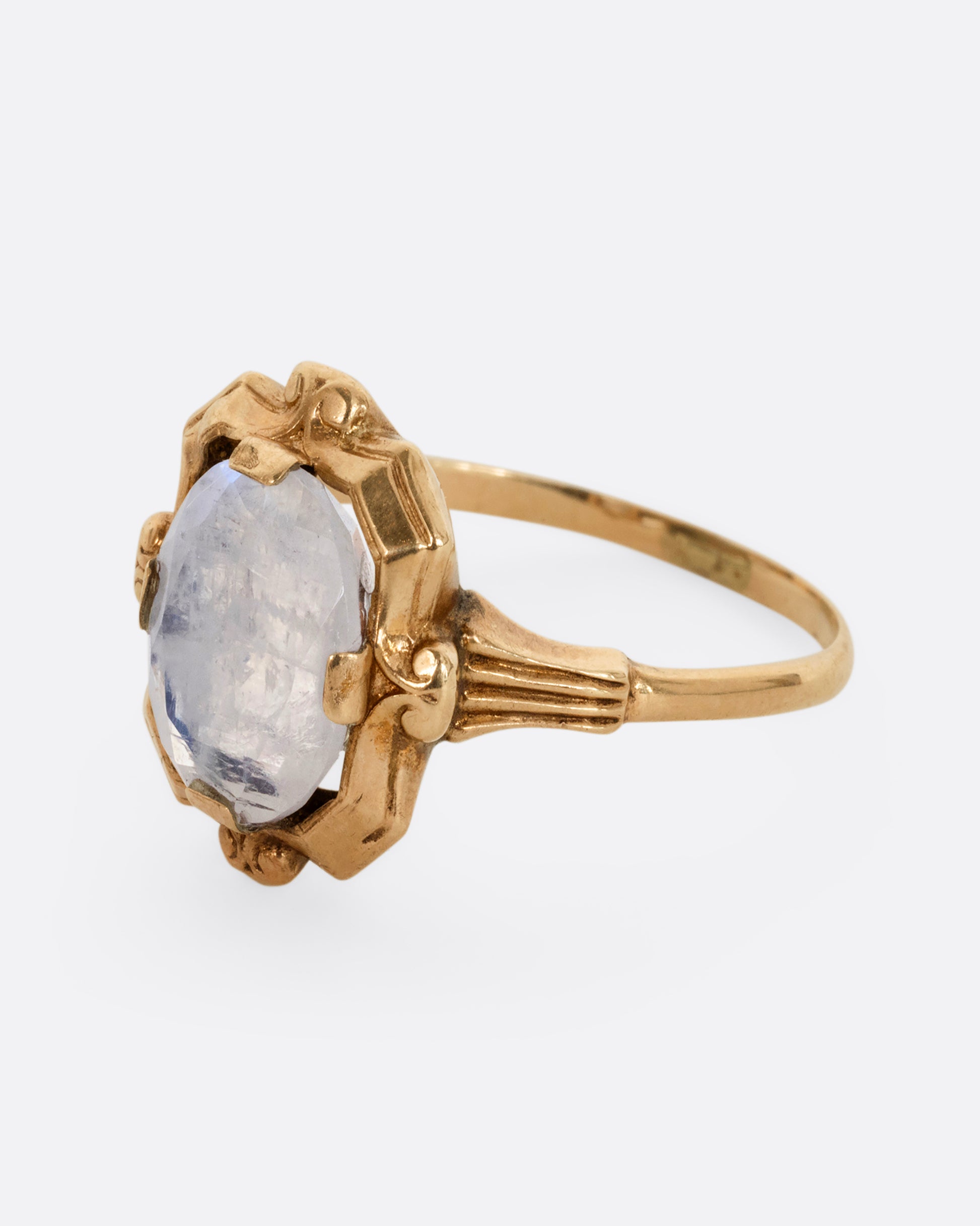 A yellow gold frame shaped ring with a moonstone at the center. Shown from the side.