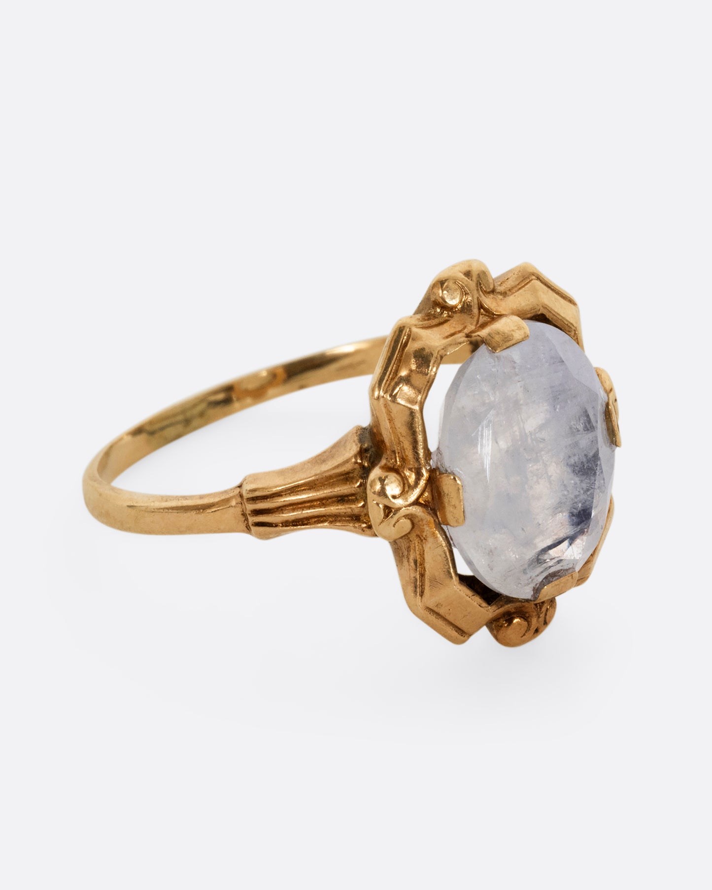 A yellow gold frame shaped ring with a moonstone at the center. Shown from the side.