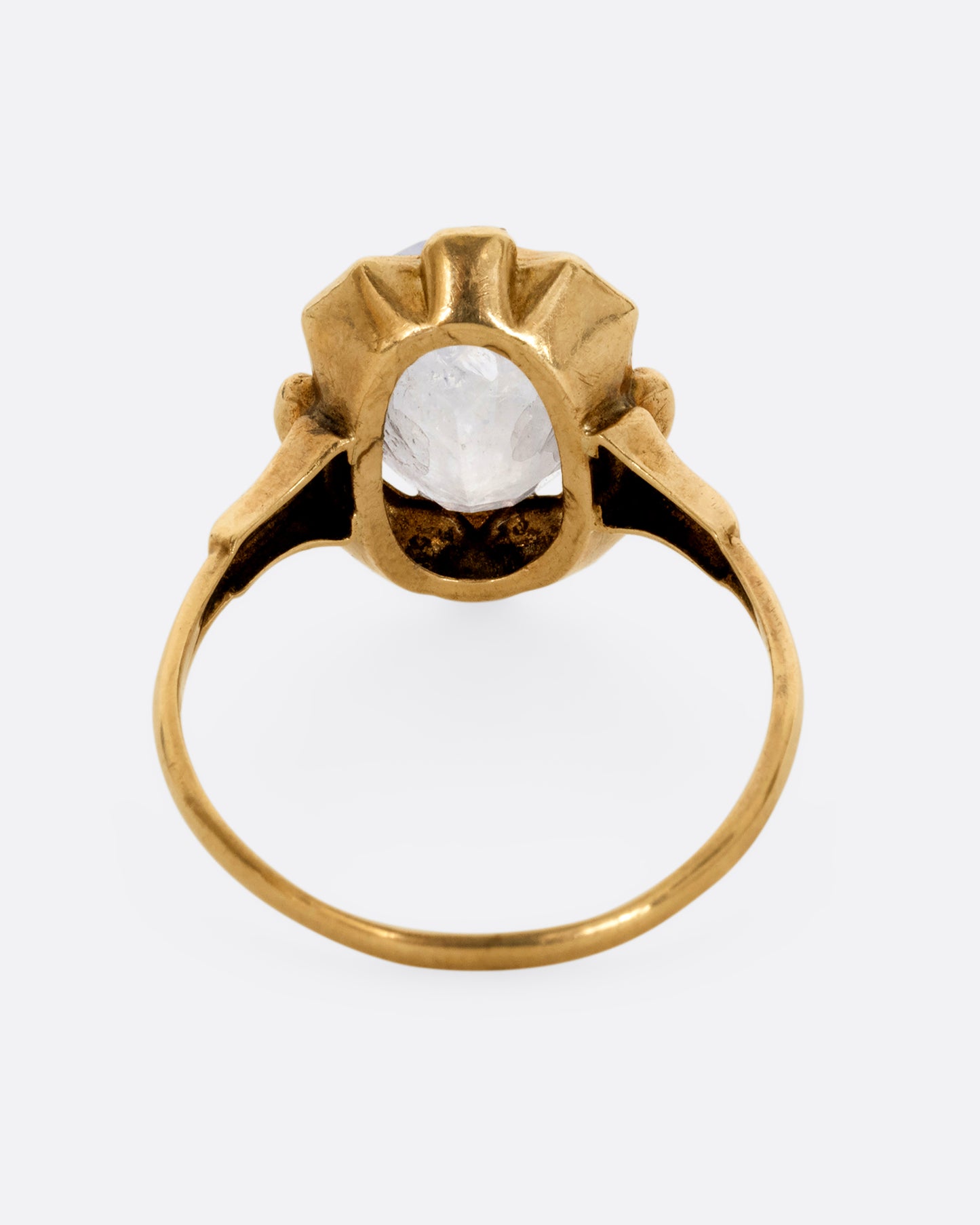 A yellow gold frame shaped ring with a moonstone at the center. Shown from the back.