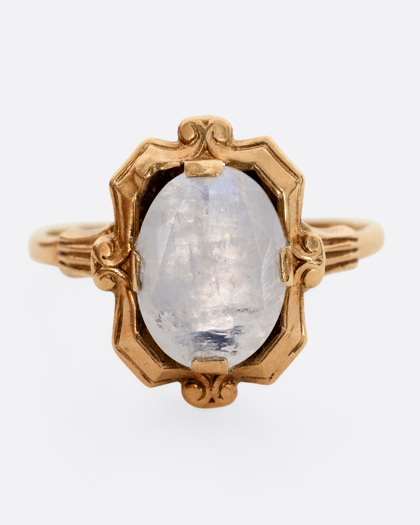 A yellow gold frame shaped ring with a moonstone at the center. Shown from the front.