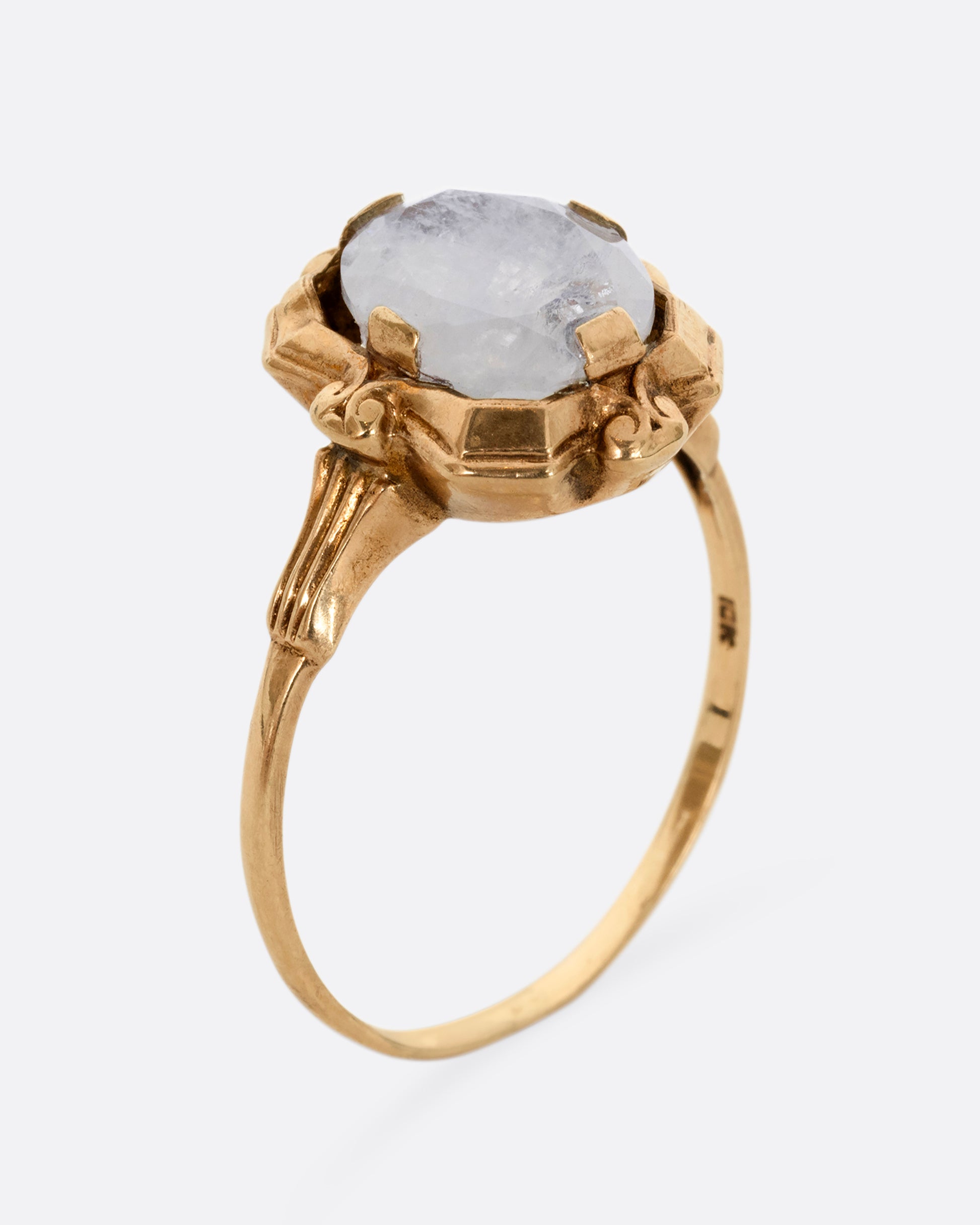 A yellow gold frame shaped ring with a moonstone at the center. Shown from the side, standing up.