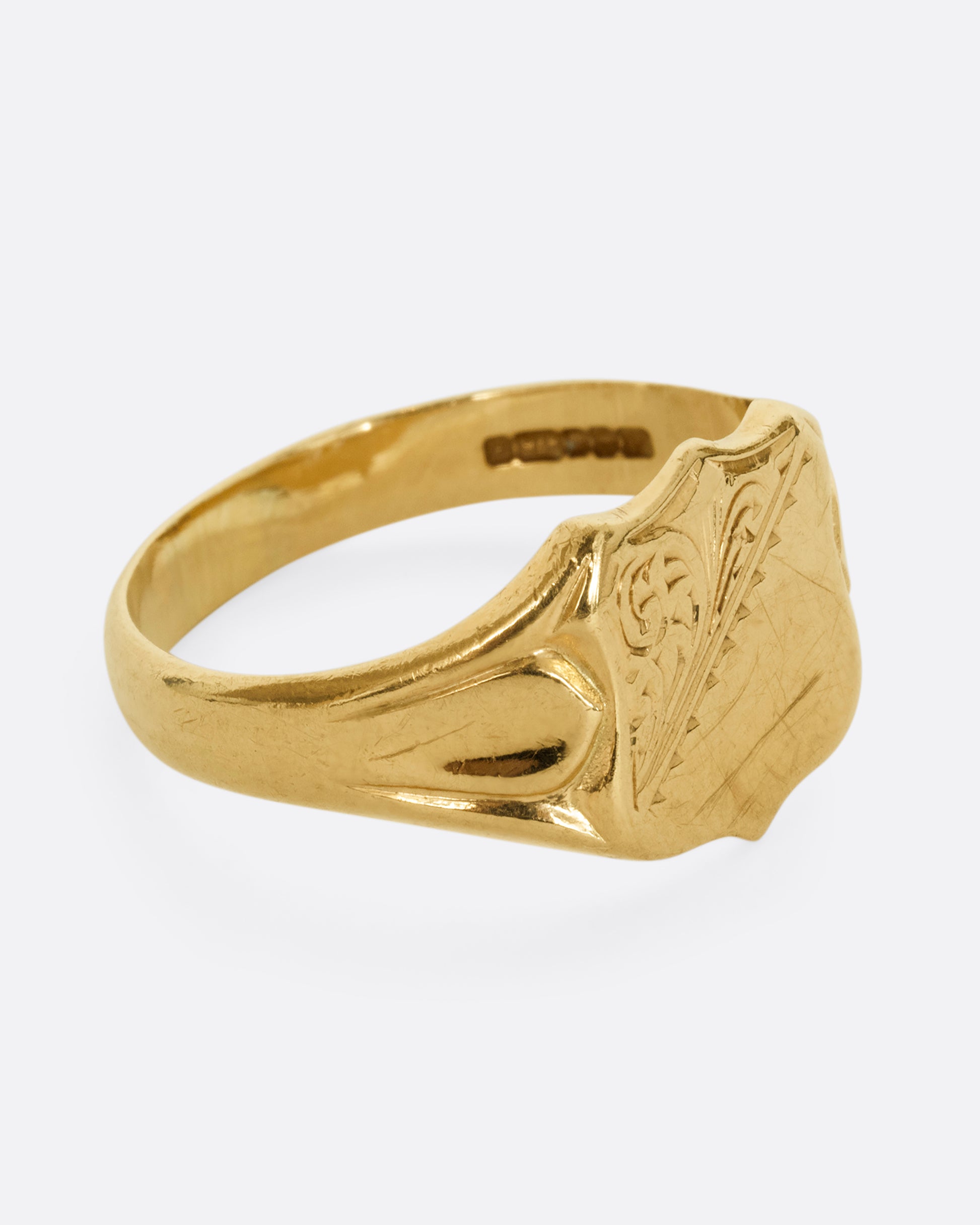 A yellow gold shield signet ring. Shown from the side.