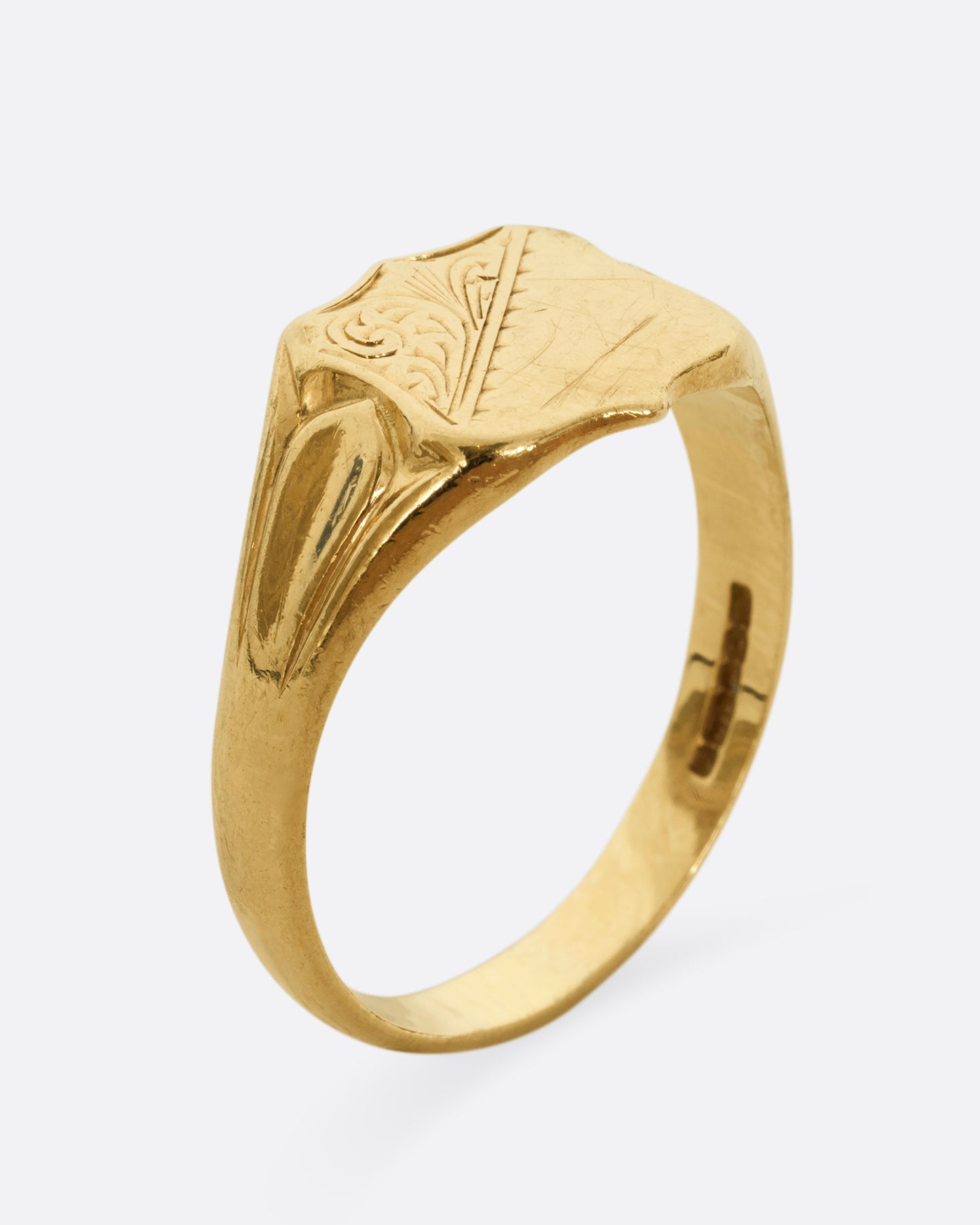 A yellow gold shield signet ring. Shown from the side, standing up.