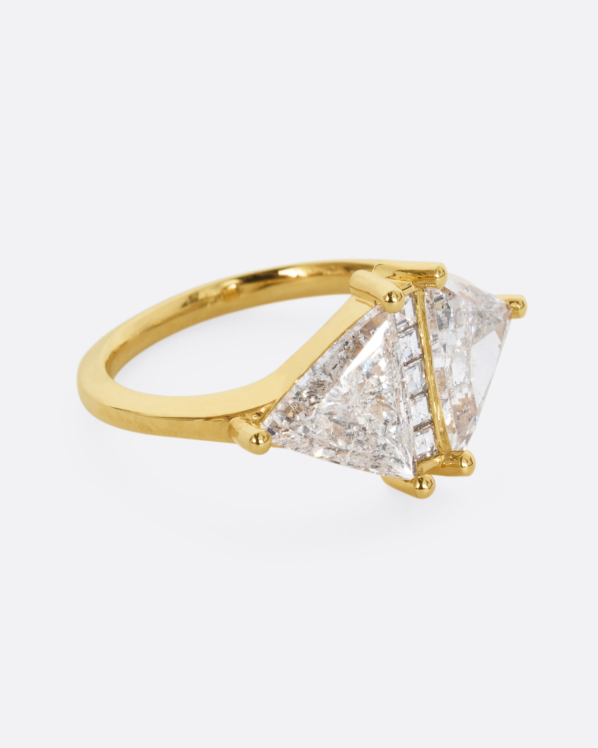 A yellow gold ring with two salt and pepper trillion cut diamonds and diamond accents. Shown from the side.