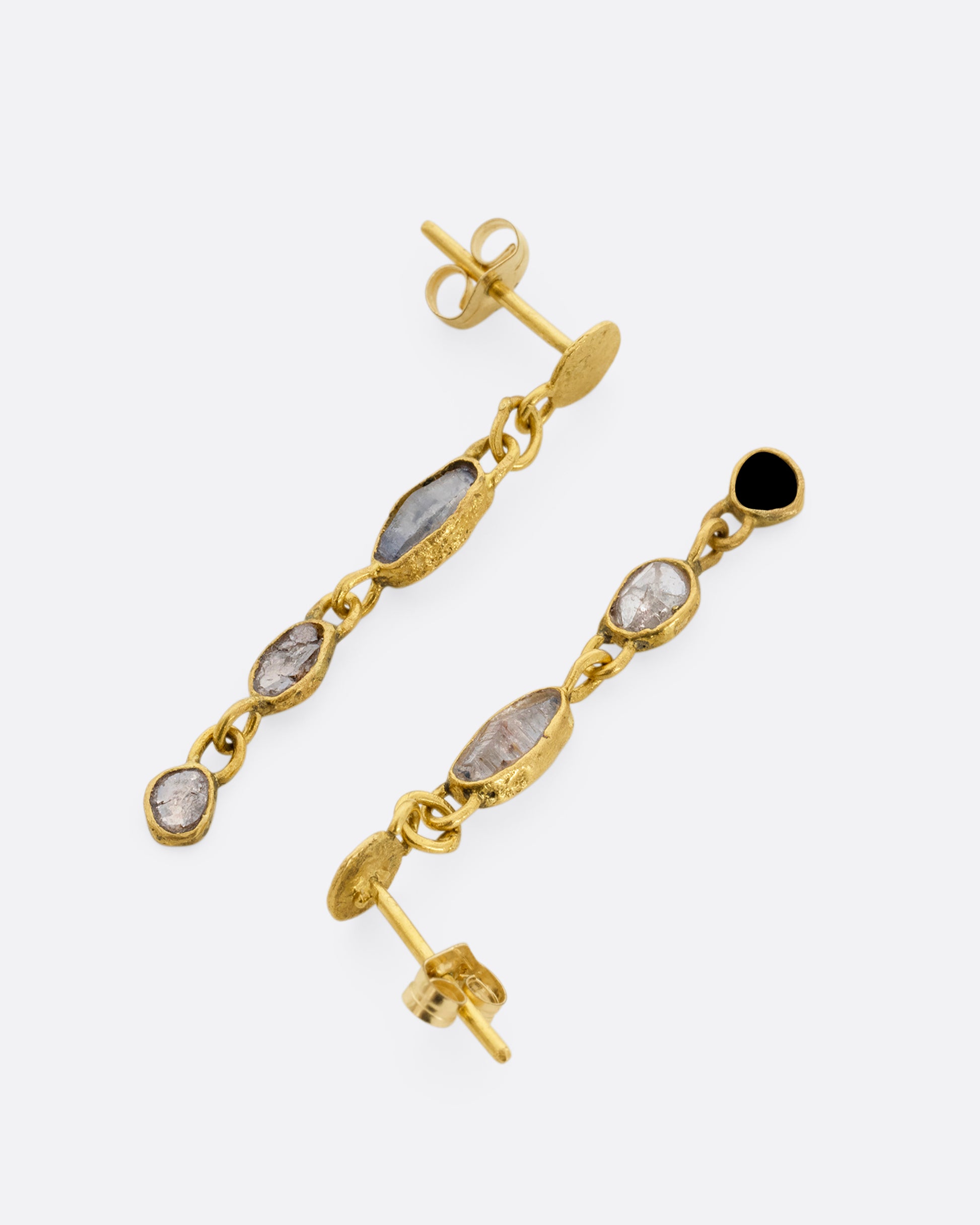 Yellow gold wrapped sapphire and  diamond earrings falling  from hammered gold discs. Shown from the side facing opposite directions.