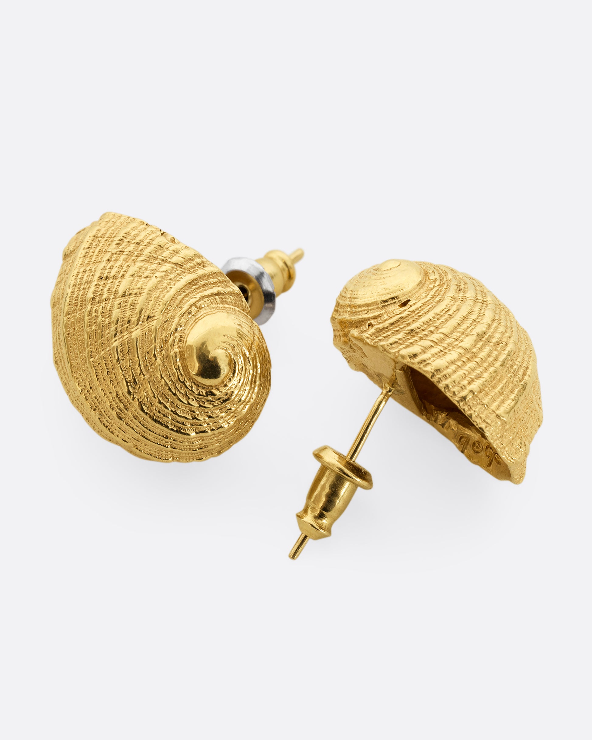 A pair of yellow gold earrings in the shape of a shell. Shown laying flat.