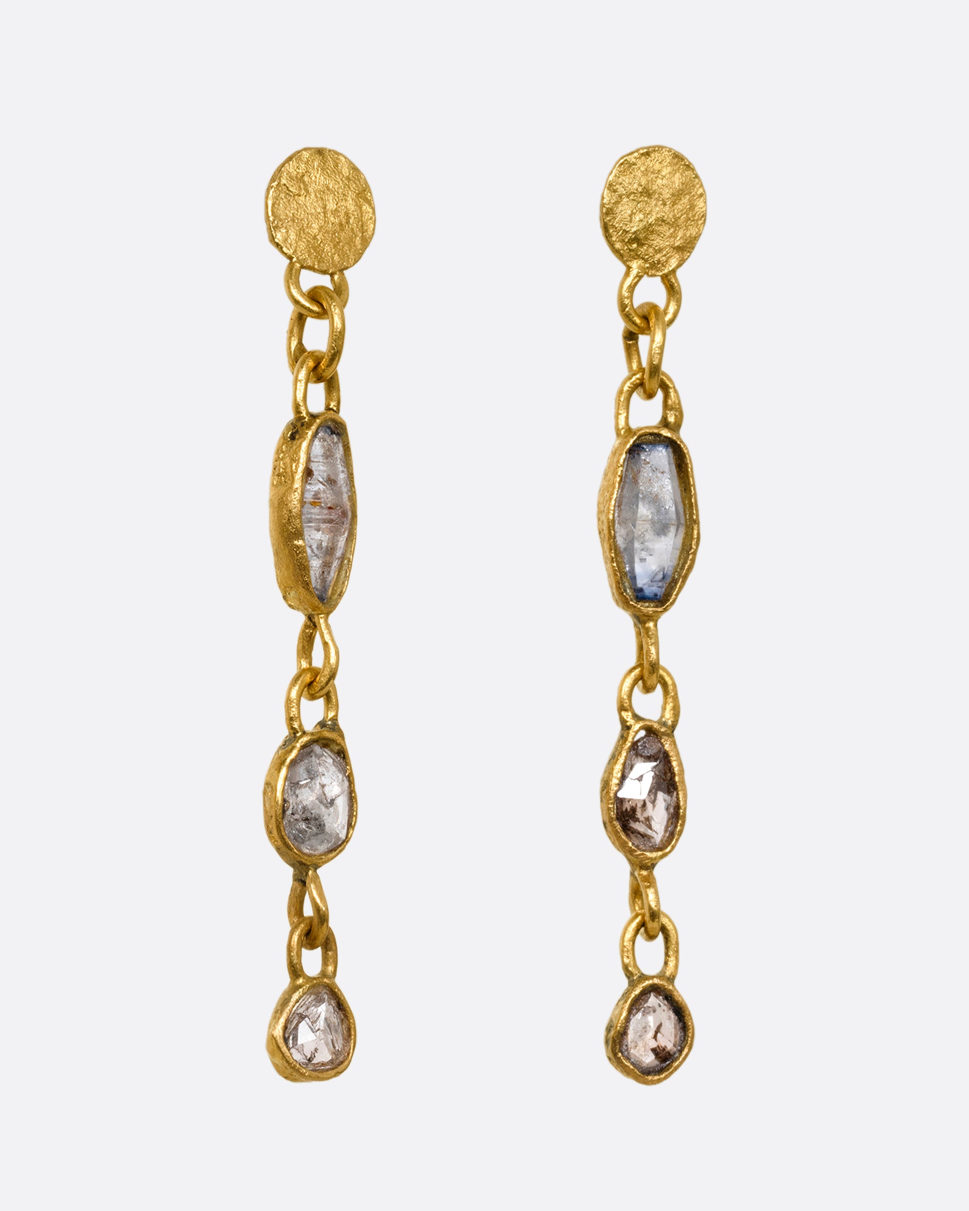 Yellow gold wrapped sapphire and  diamond earrings falling  from hammered gold discs. Shown from the side.