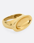 A yellow gold ring with a broad oval signet with a slight concave, shown from the side.