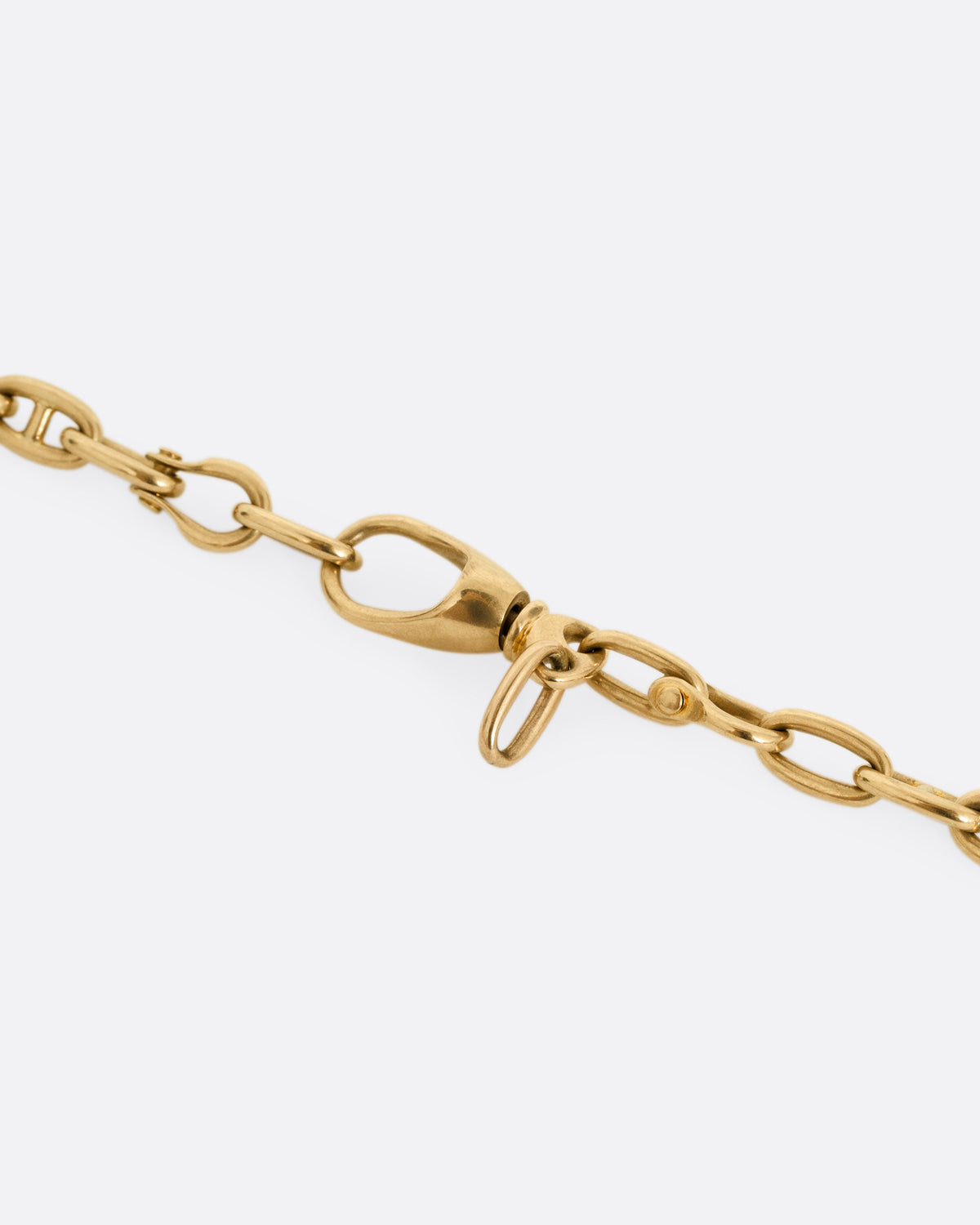 A close up of the clasp of a rose gold mariner watch chain necklace.