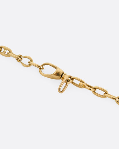 A close up of the clasp of a rose gold mariner watch chain necklace.