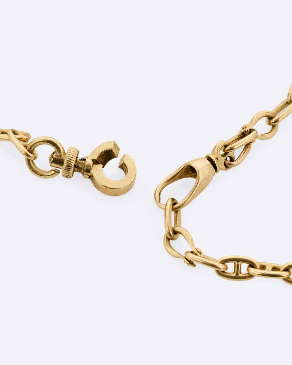 A close up of a rose gold mariner watch chain necklace, shown open.